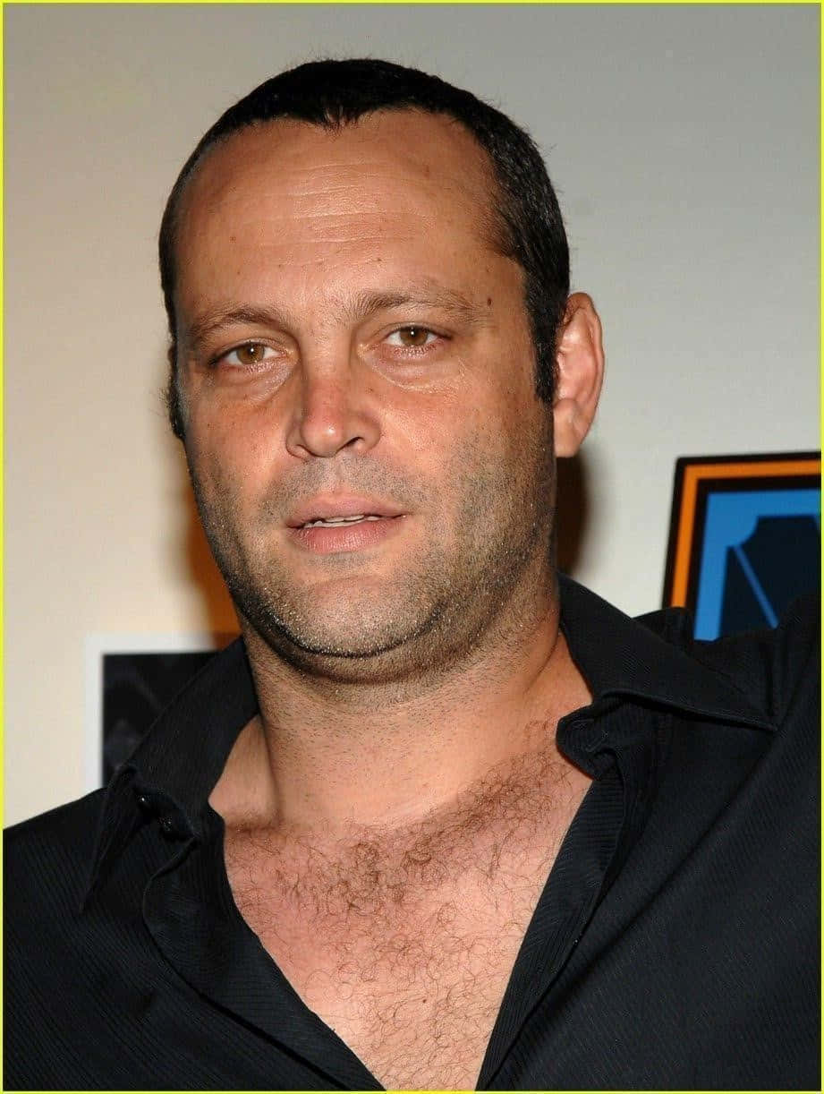 Vince Vaughn 桌布 壁紙 — 一名短黑髮、鬍渣男子穿著黑色有領襯衫，在純色背景前的特寫肖像。