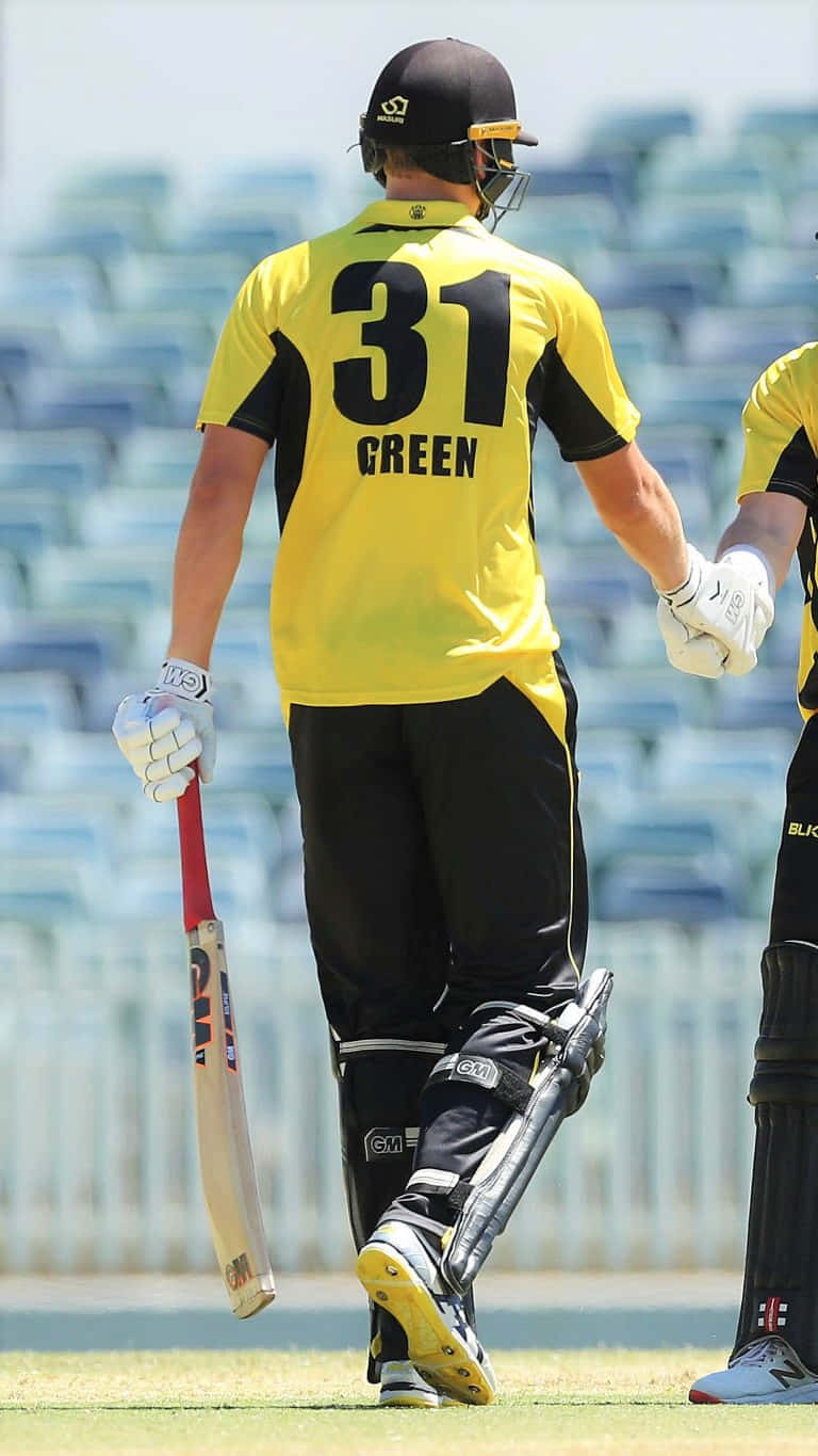 Cameron Green 桌布 壁紙 — 一名穿着黃黑相間制服、背號31的板球運動員手持球棒，在草地上背對鏡頭走開。