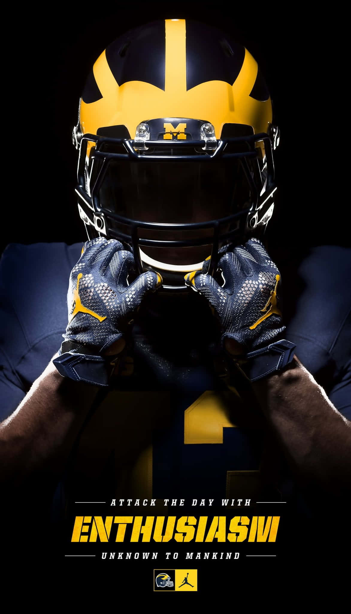 Michigan Wolverines 桌布 壁紙 — 一名穿著密歇根頭盔的足球運動員在黑色背景前抓住面罩，下方有粗體黃色文字。