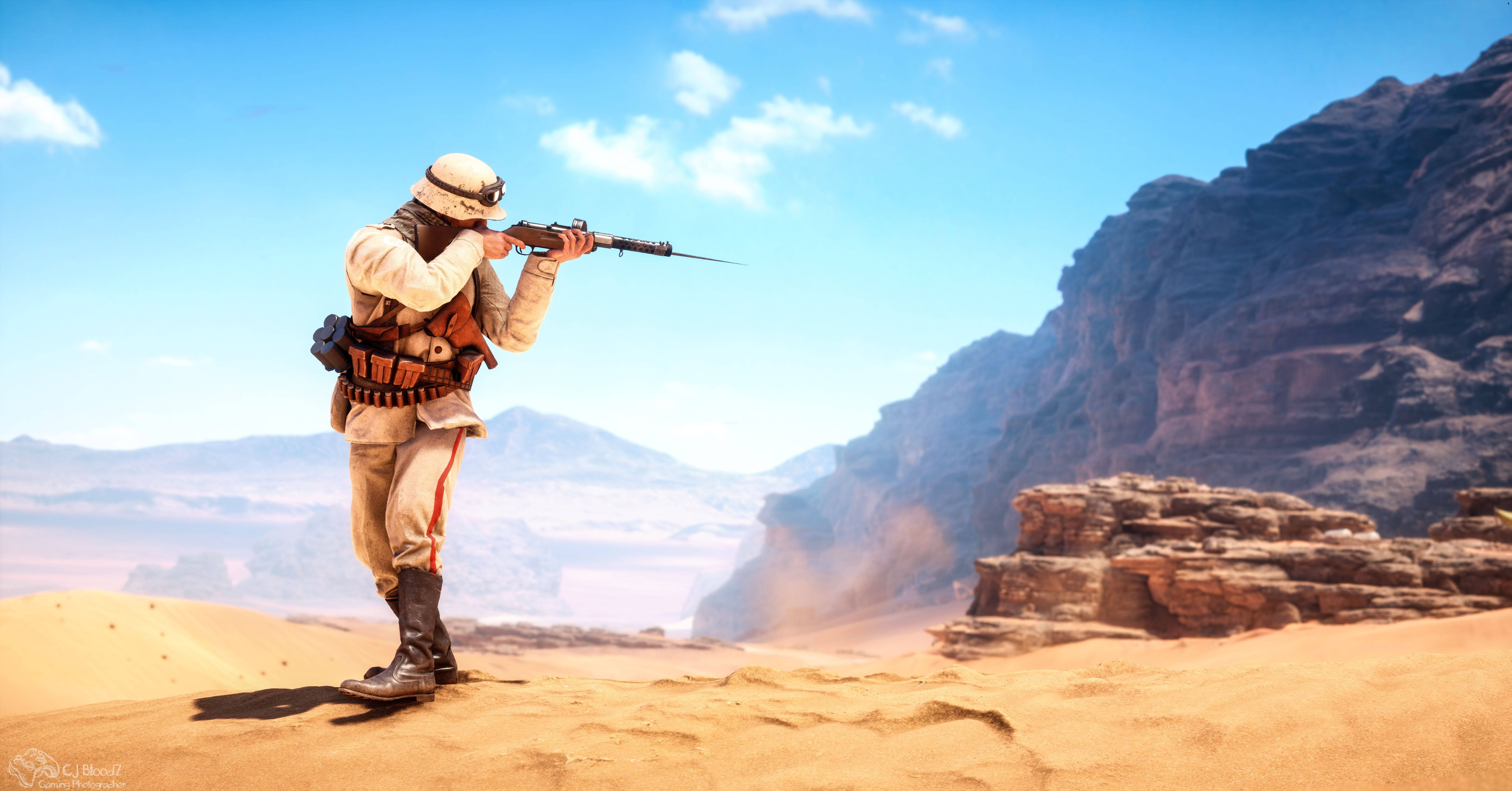 Battlefield 1 HD 桌布 壁紙 — 一名穿著沙漠裝備的士兵在沙丘上瞄準步槍，俯瞰崎嶇的峽谷懸崖，天空湛藍。