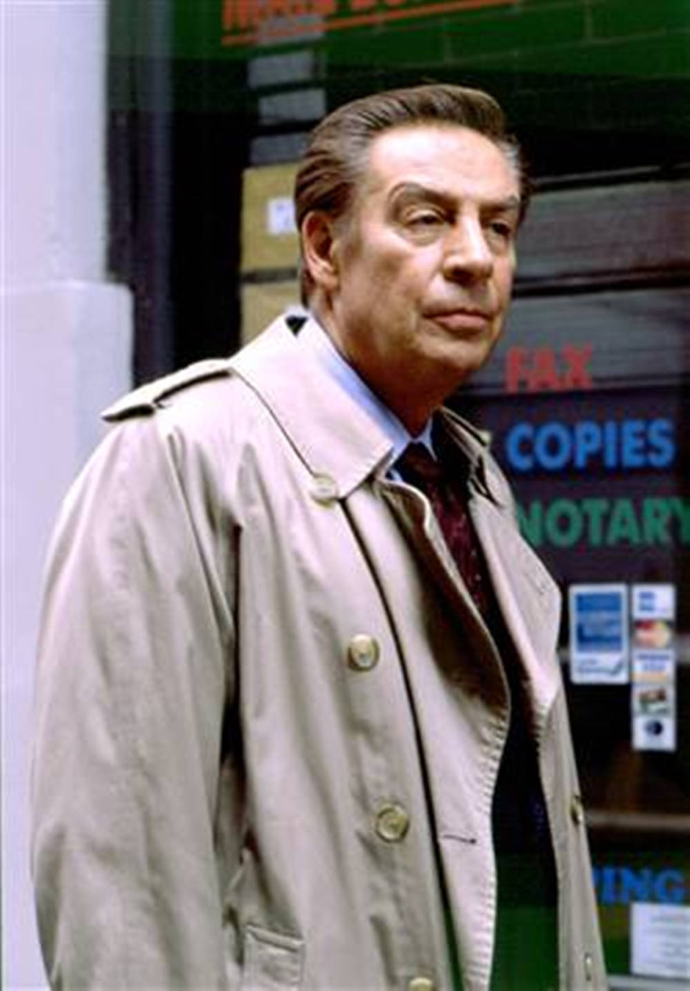 Jerry Orbach In Brown Coat Law And Order 壁紙 — 一名穿著米色風衣的男子站在商店門外，身後可見「FAX COPIES NOTARY」的標牌。