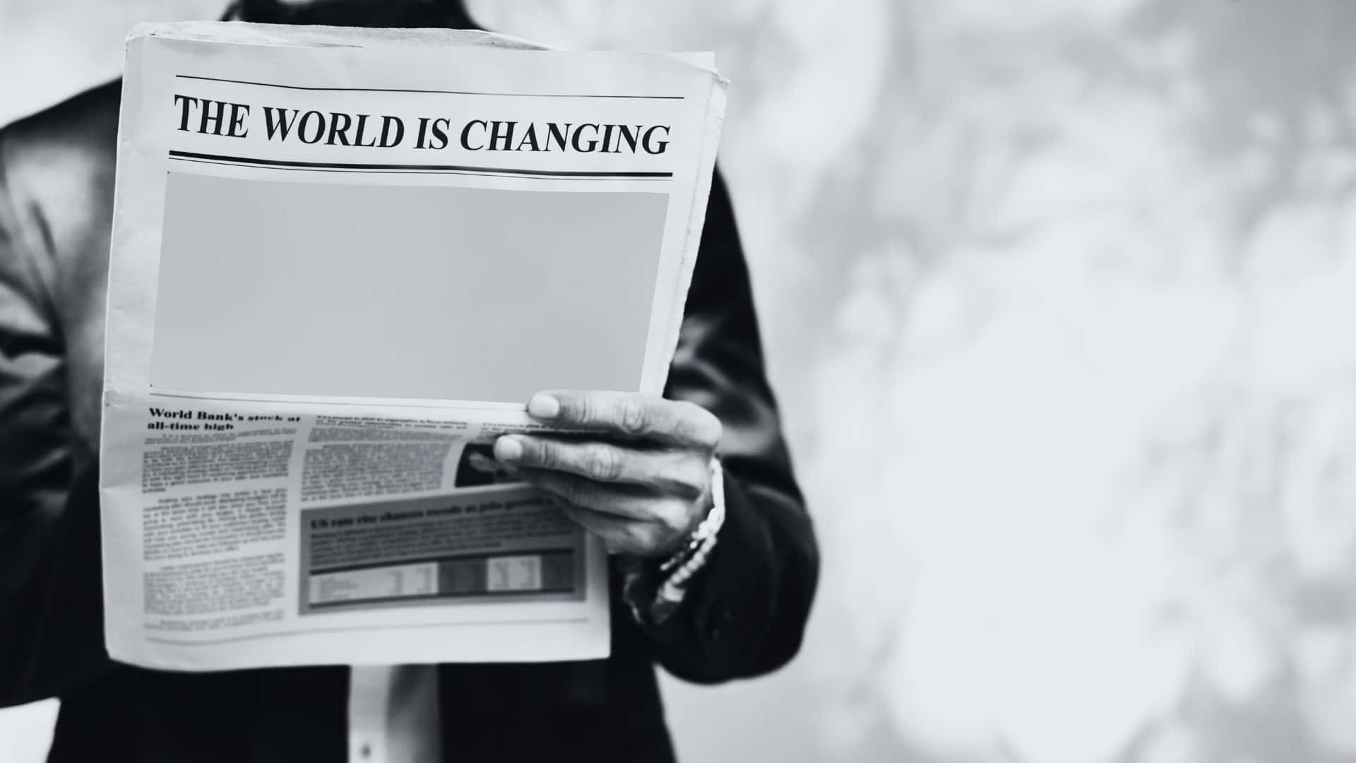 Black And White Newspaper 桌布 壁紙 — 一名穿著西裝的人手持報紙，標題為「世界正在改變」，以鮮明的黑白呈現。