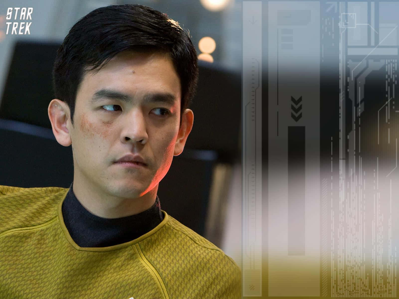 John Cho 桌布 壁紙 — 一名穿著黃色制服嘅星際迷航官員喺未來感十足嘅太空船走廊入面專注咁望住鏡頭外。