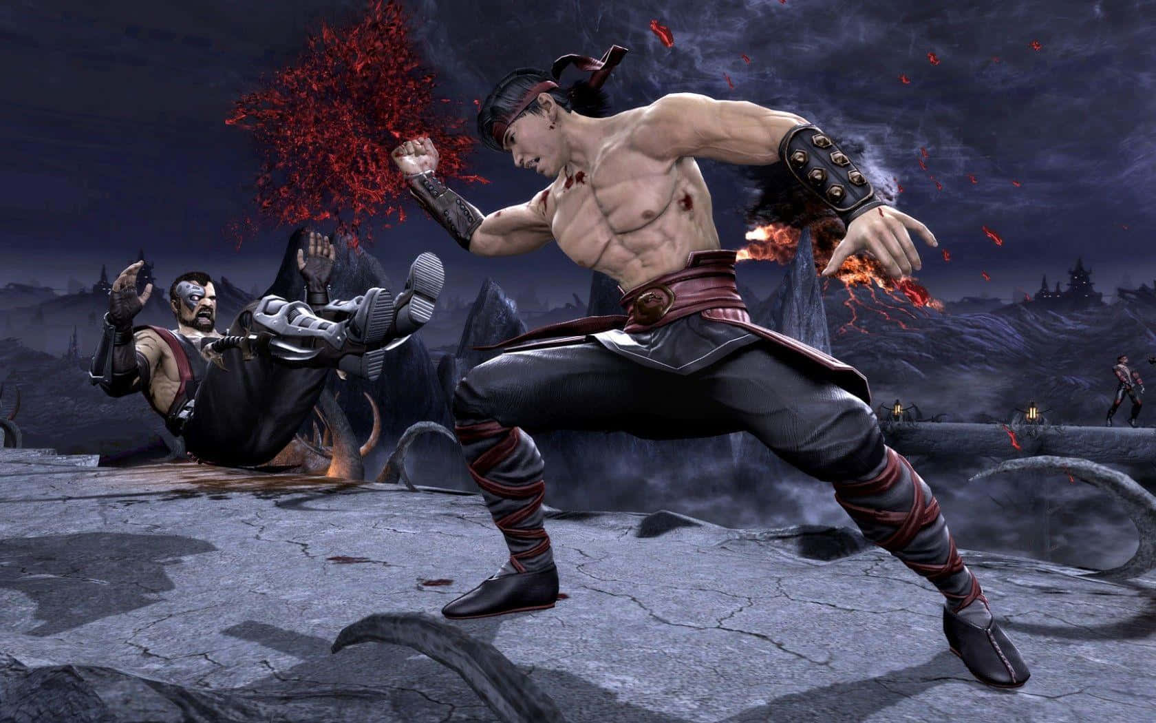 Mortal Kombat Kano 桌布 壁紙 — 一名肌肉發達的戰士身穿紅黑裝備，在黑暗的火山戰場上，伴隨著飛舞的紅色粒子，向對手踢出強力一腳。