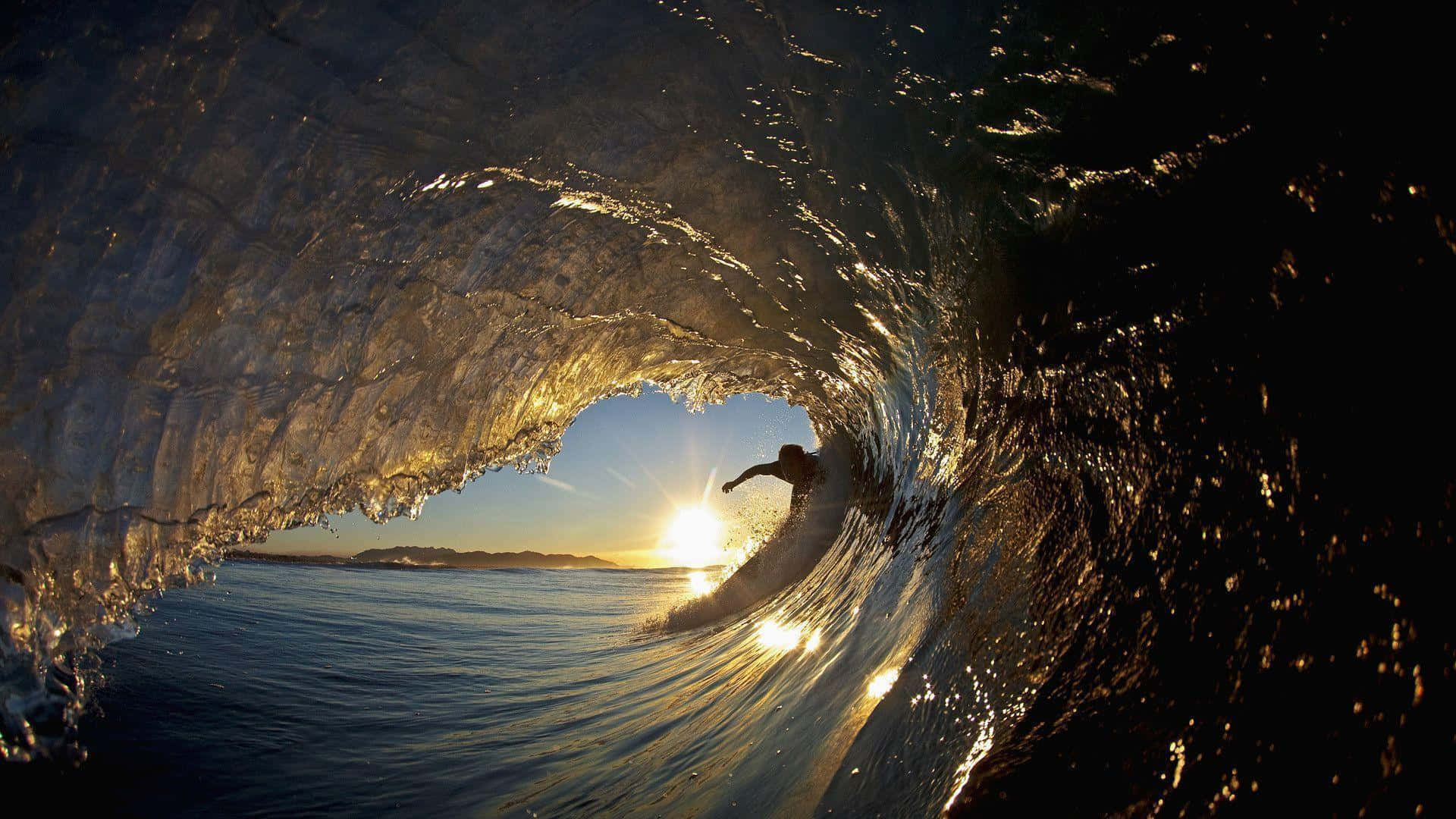 surfing 桌布 壁紙 — 一名衝浪者在日落時分，在金光閃閃的陽光照射下的海洋波浪隧道內衝浪，海水閃閃發光。