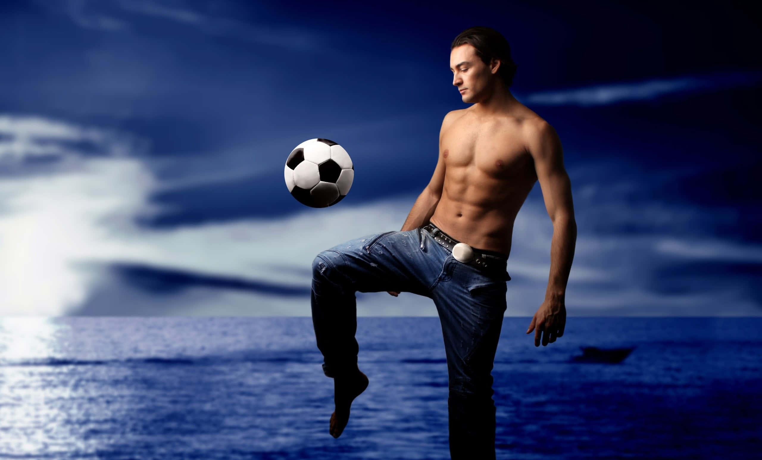 Football Players 桌布 壁紙 — 一名赤膊肌肉男在戲劇性的藍色海洋和暴風雨天空背景下用腳平衡足球。