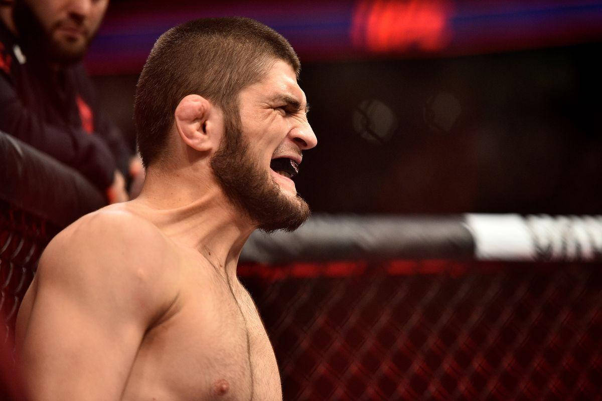 UFC 桌布 壁紙 — 一名赤裸上身的拳手在紅色燈光的八角籠內，於綜合格鬥比賽中勝利咆哮。