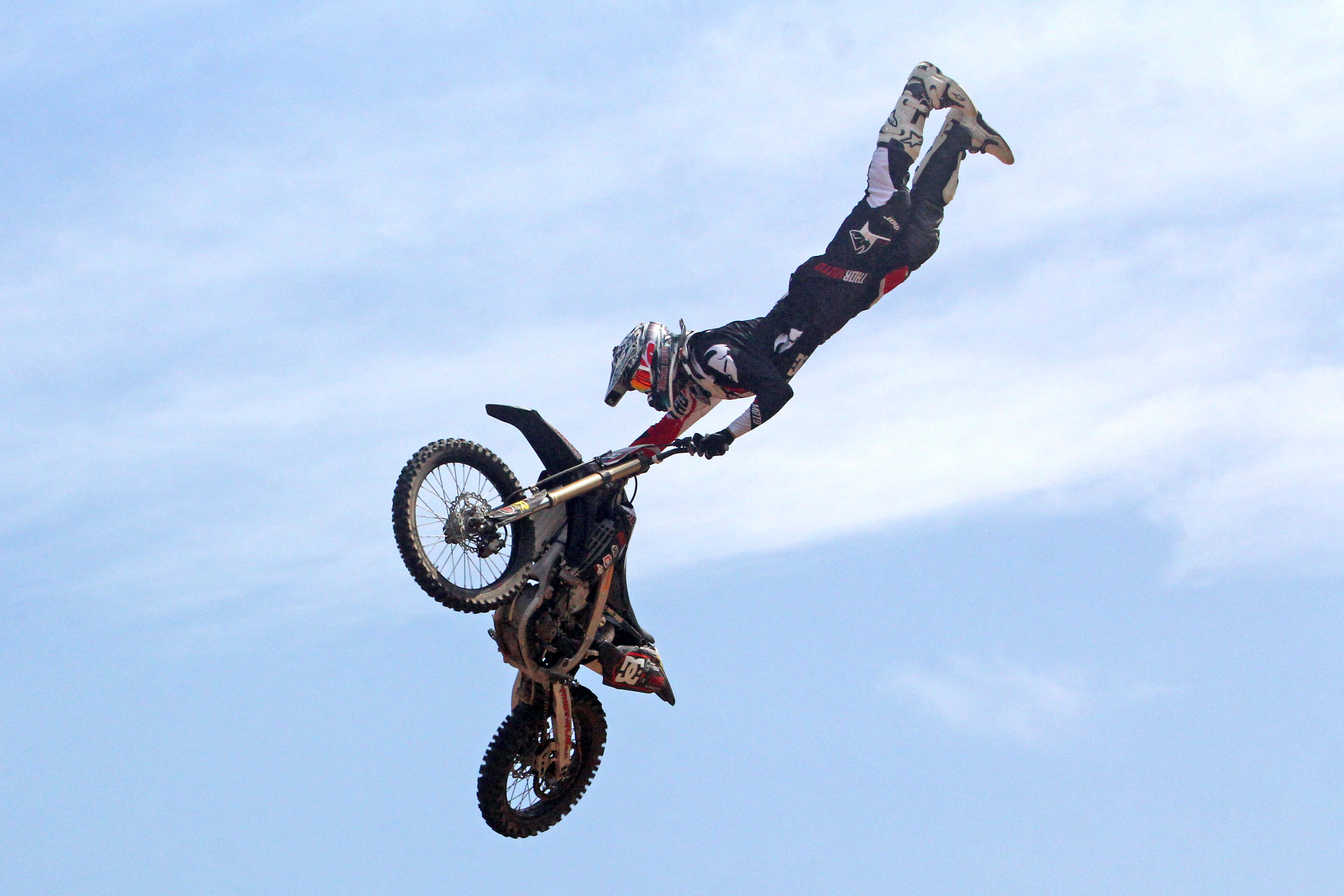Dirtbike 桌布 壁紙 — 一名越野電單車手在藍天白雲下表演倒轉空中特技。