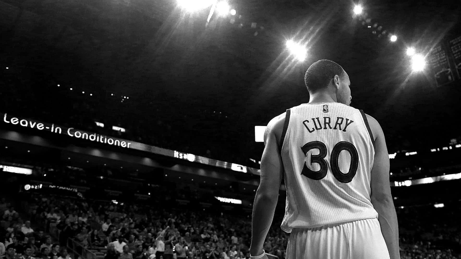steph curry 桌布 壁紙 — 一名身穿Curry 30球衣的籃球運動員獨自站在球場上，明亮的場館燈光下，背景是人群。