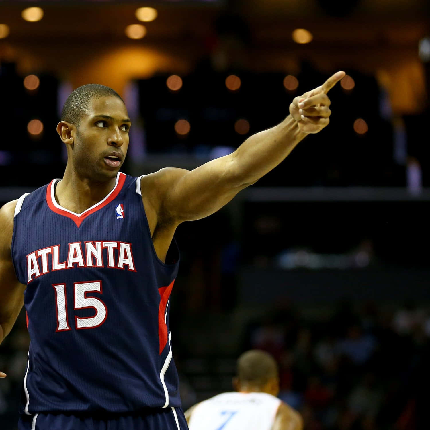 Al Horford 桌布 壁紙 — 一名身穿亞特蘭大球衣的籃球運動員在場館燈光下比賽時，充滿強度地向前指。