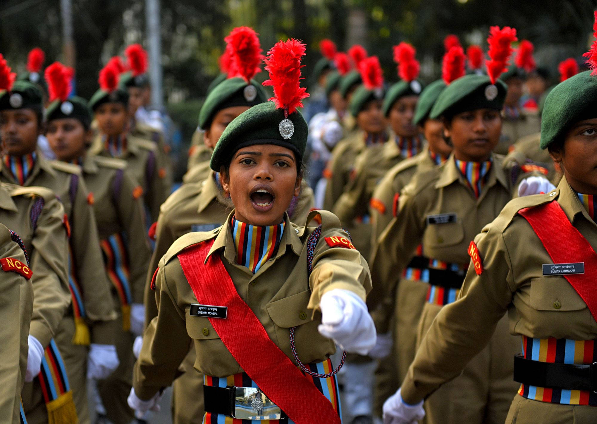Indian Army 桌布 壁紙 — 一名身穿卡其色制服、戴紅色羽毛貝雷帽的年輕女兵在閱兵中專注地向前行進。