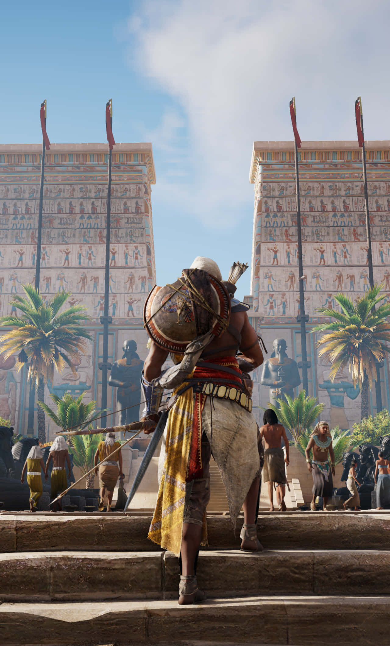 Bayek 桌布 壁紙 — 一名身穿古埃及服飾的戰士站在石階上，面對著刻滿象形文字的宏偉塔門，背景是明亮的藍天。