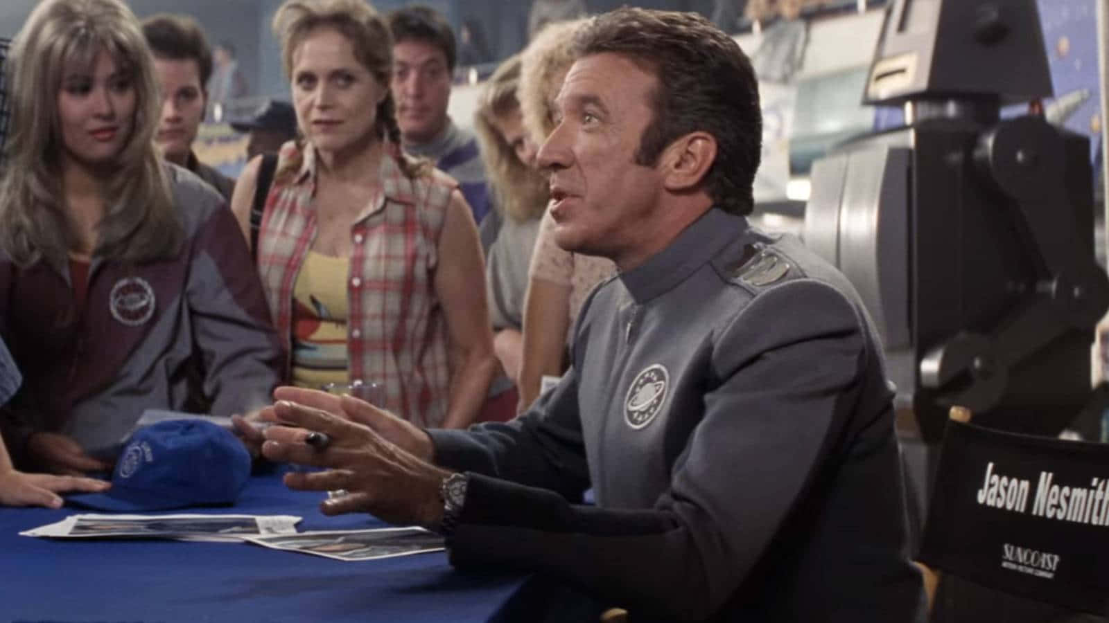 Galaxy Quest 桌布 壁紙 — 一名身穿太空總署制服嘅男人喺粉絲活動中簽名，人群圍觀。