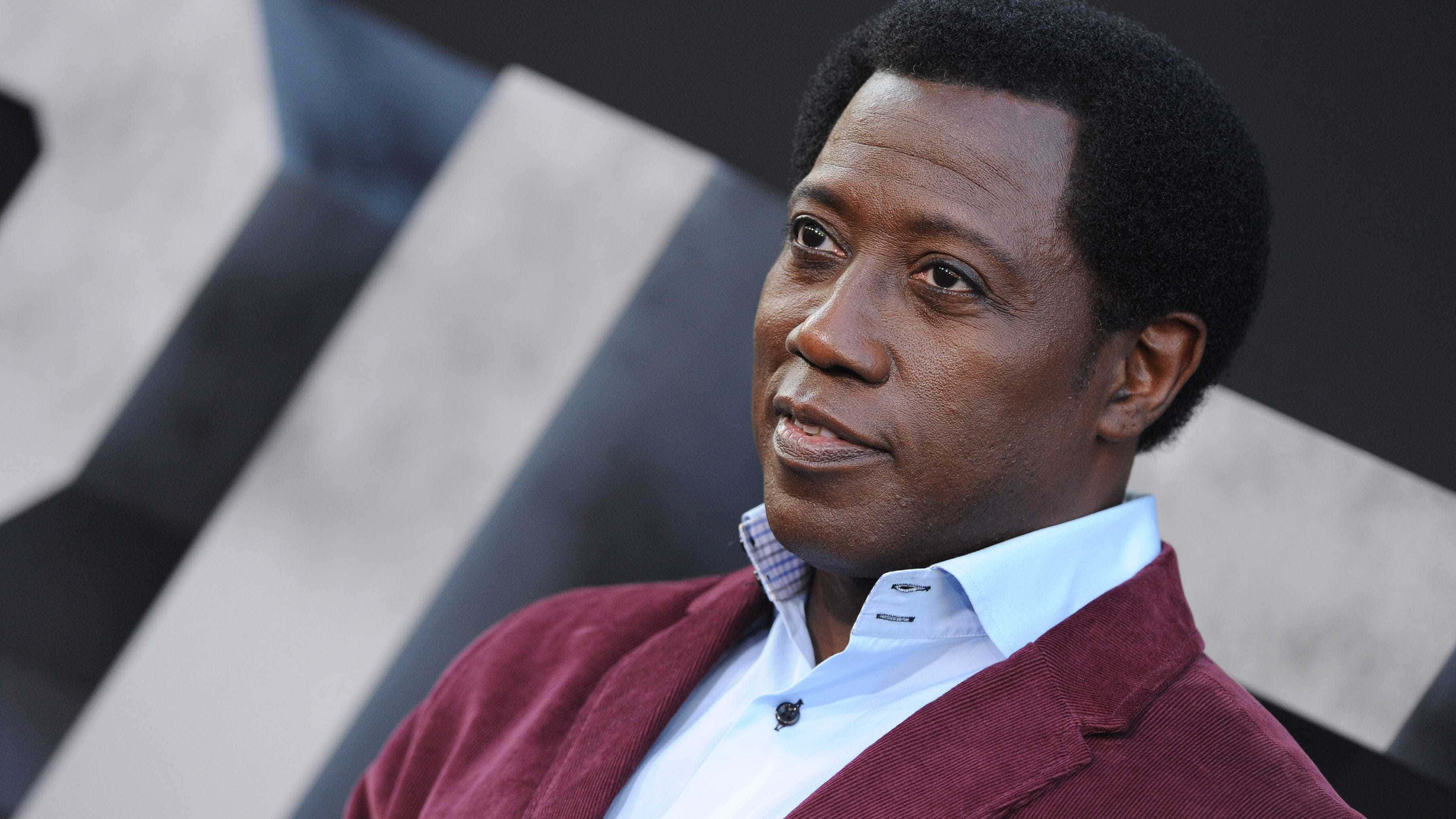 Wesley Snipes 桌布 壁紙 — 一名身穿栗色西裝外套和白色襯衫的男子，在幾何黑白背景前若有所思地望向一旁。