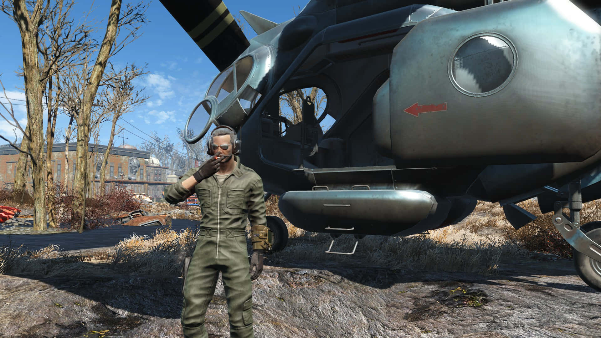 Fallout 4 The Capital Wasteland 桌布 壁紙 — 一名身穿橄欖綠軍服的士兵，在晴朗藍天下，站在荒涼的末日後廢土中一架生鏽的軍用直升機旁。