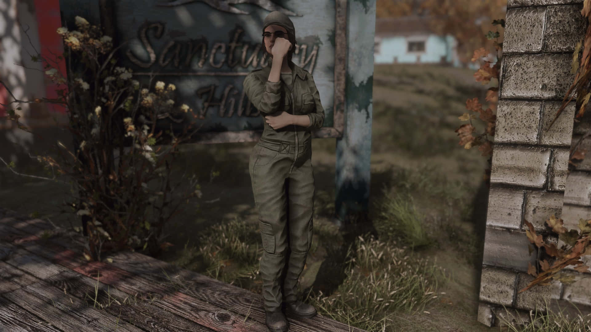 Fallout 4 The Capital Wasteland 桌布 壁紙 — 一名身穿橄欖綠軍裝的人沉思地站在一個破舊的鄉村環境中，旁邊是一個寫著 Sanctuary Hill 的風化標誌。