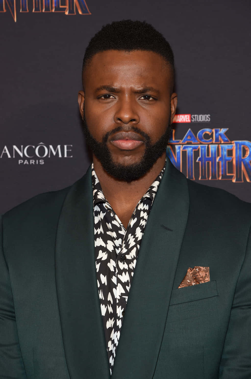 Winston Duke 桌布 壁紙 — 一名身穿深綠色西裝和圖案襯衫的男子自信地站在黑豹首映活動中。