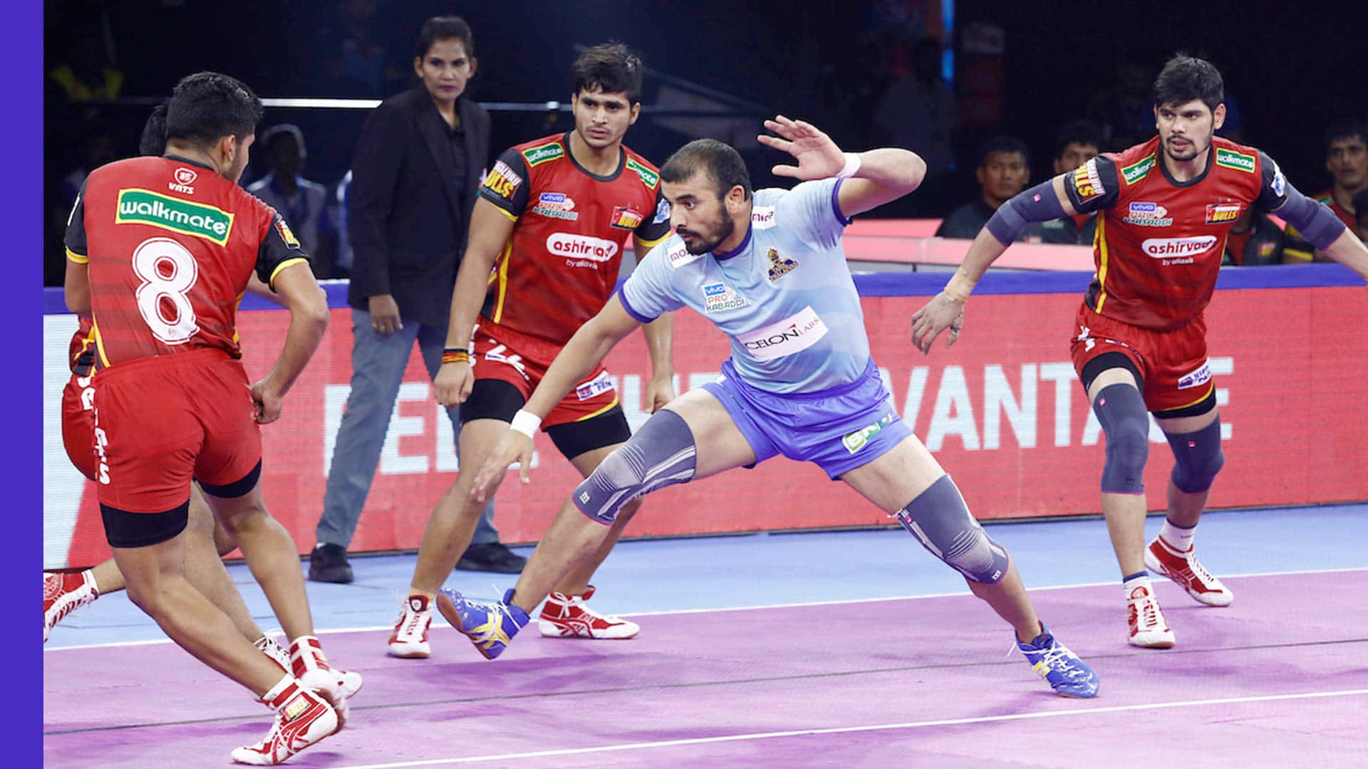 Kabaddi 桌布 壁紙 — 一名身穿淺藍色球衣的男子手球運動員向前衝刺投球，而身穿紅色球衣的防守球員在激烈的室內比賽中逼近。