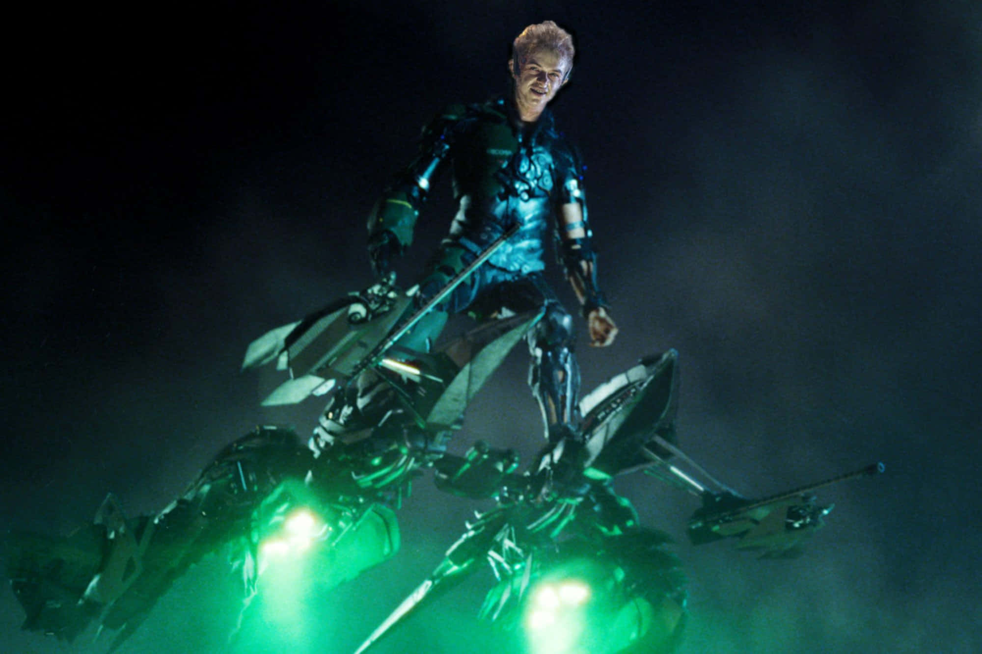 Harry Osborn 桌布 壁紙 — 一名身穿發光綠色盔甲的未來戰士站在機械車輛上，背景是黑暗煙霧彌漫。