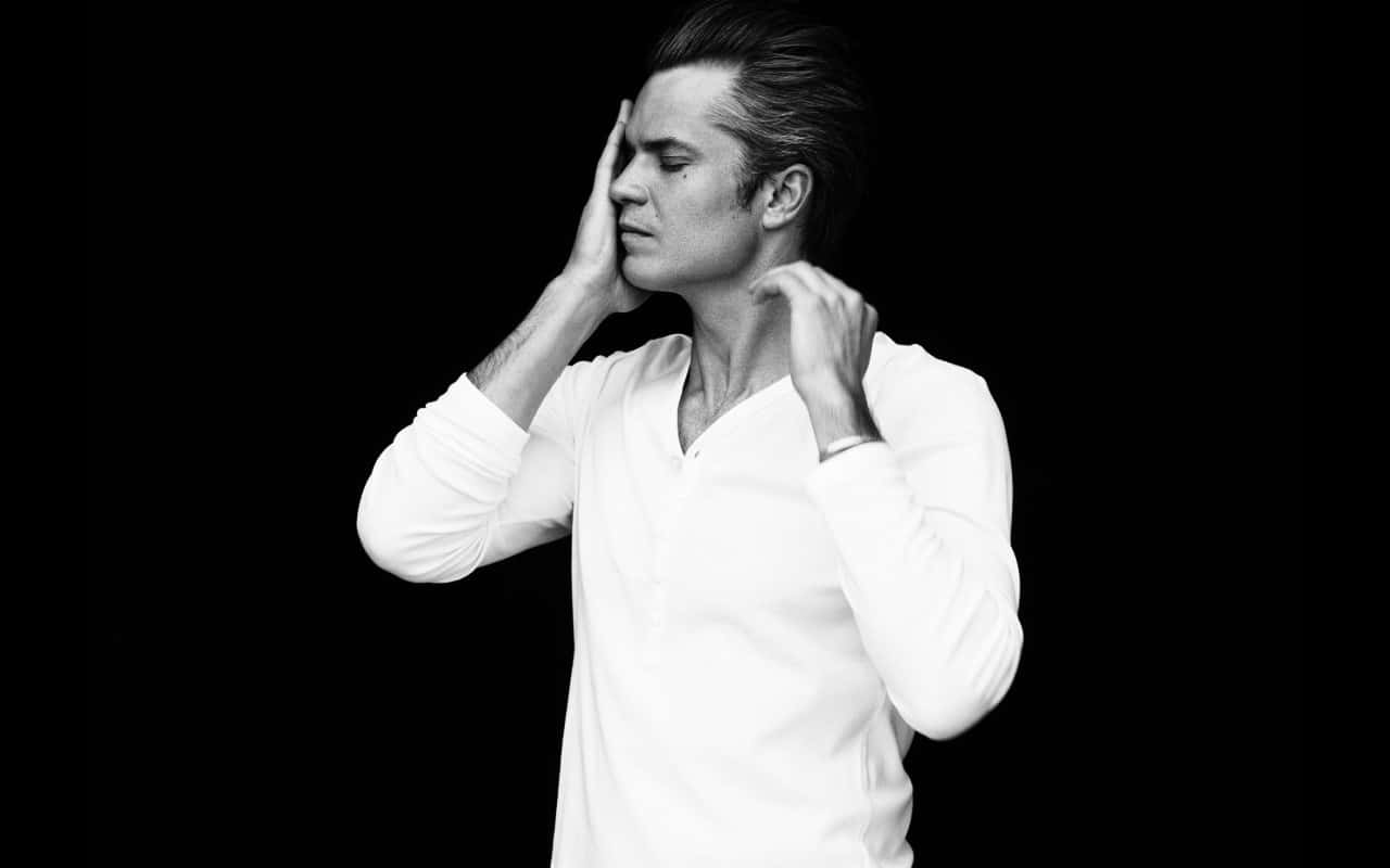 timothy olyphant 桌布 壁紙 — 一名身穿白恤衫的男子站在黑色背景前，雙手靠近臉部，擺出沉思的姿勢。