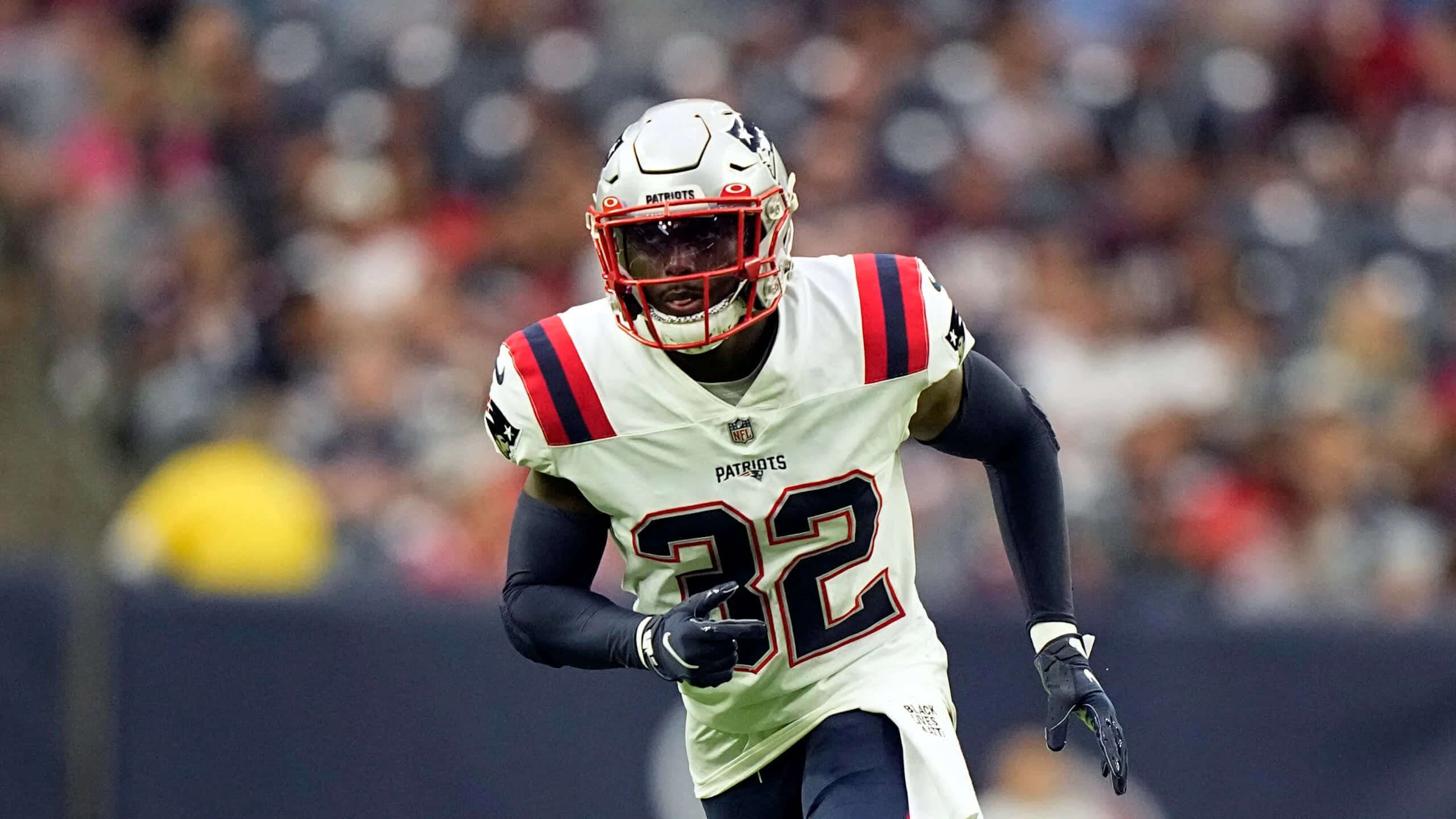 Devin Mccourty 桌布 壁紙 — 一名身穿白色32號球衣的新英格蘭愛國者美式足球員在球場燈光下比賽中全力衝刺。