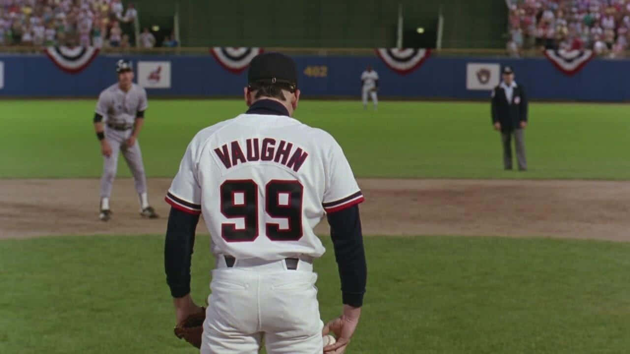Major League Movie 桌布 壁紙 — 一名身穿白色Vaughn 99球衣的棒球選手站在綠色球場上，背景有觀眾。