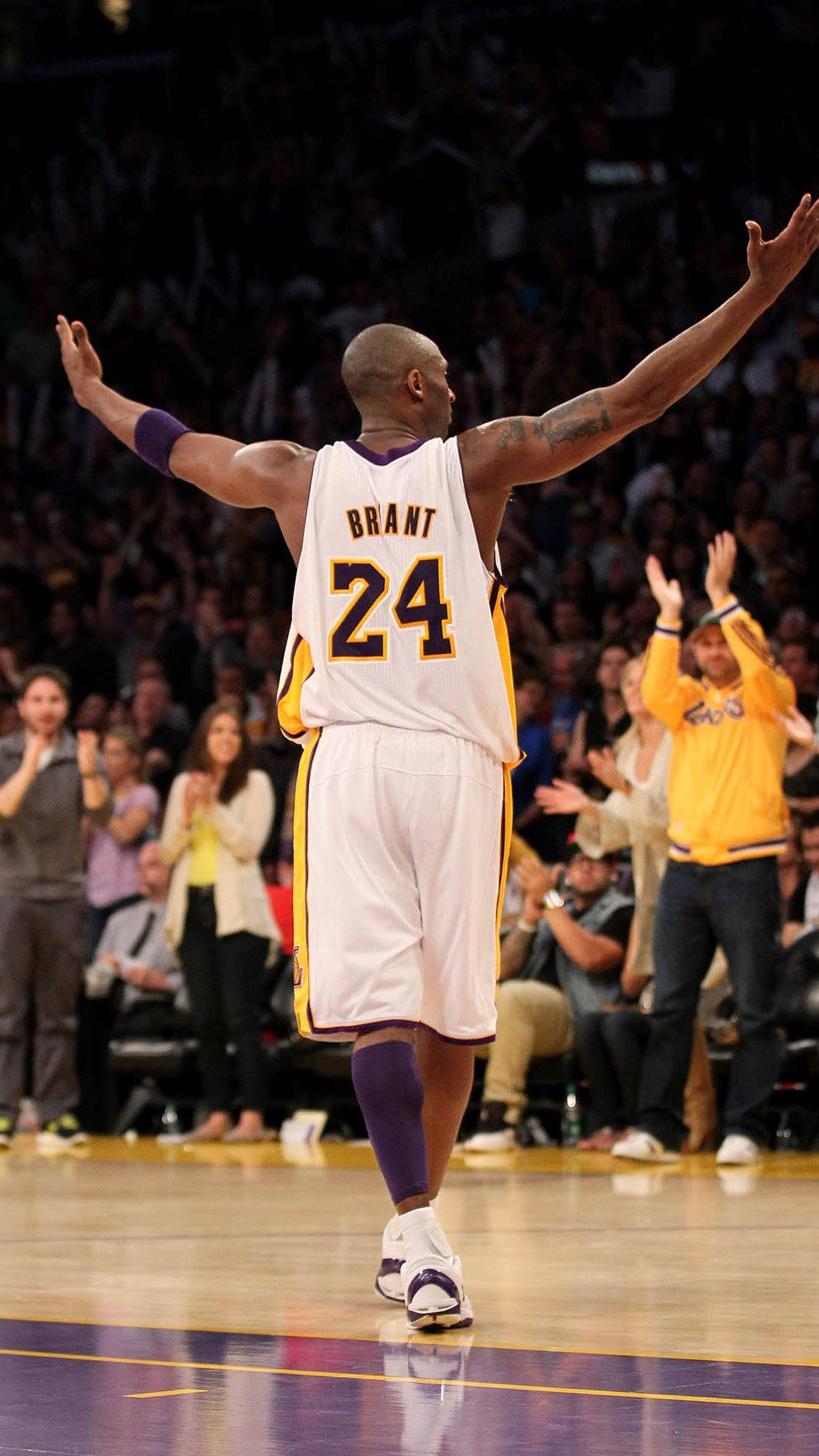 Kobe 桌布 壁紙 — 一名身穿白色和紫色球衣、背號24的籃球運動員高舉雙臂離開球場，背景中球迷歡呼。
