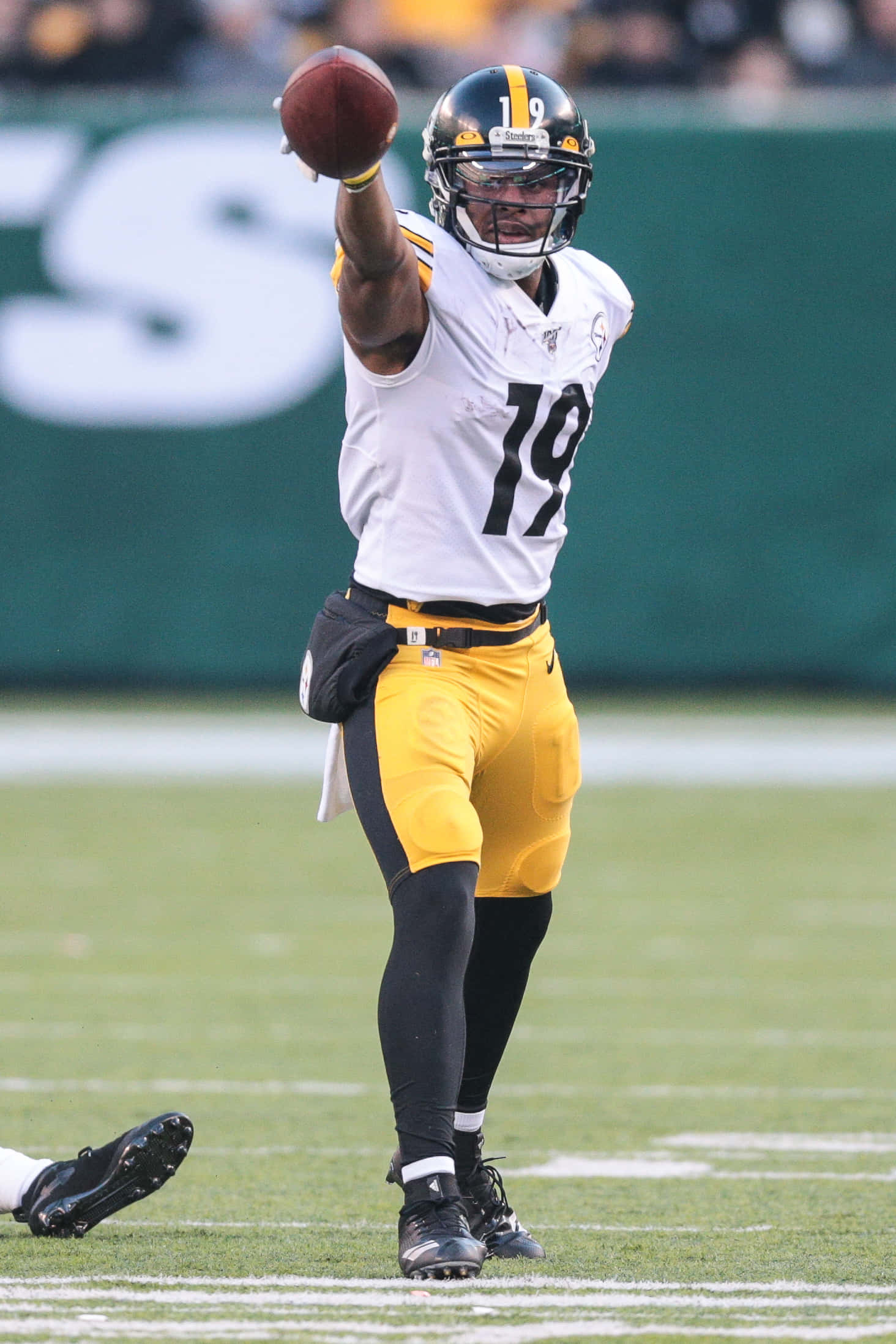 Juju Smith Schuster 桌布 壁紙 — 一名身穿白色和黃色球衣的美式足球四分衛在綠色球場上比賽時擲球。
