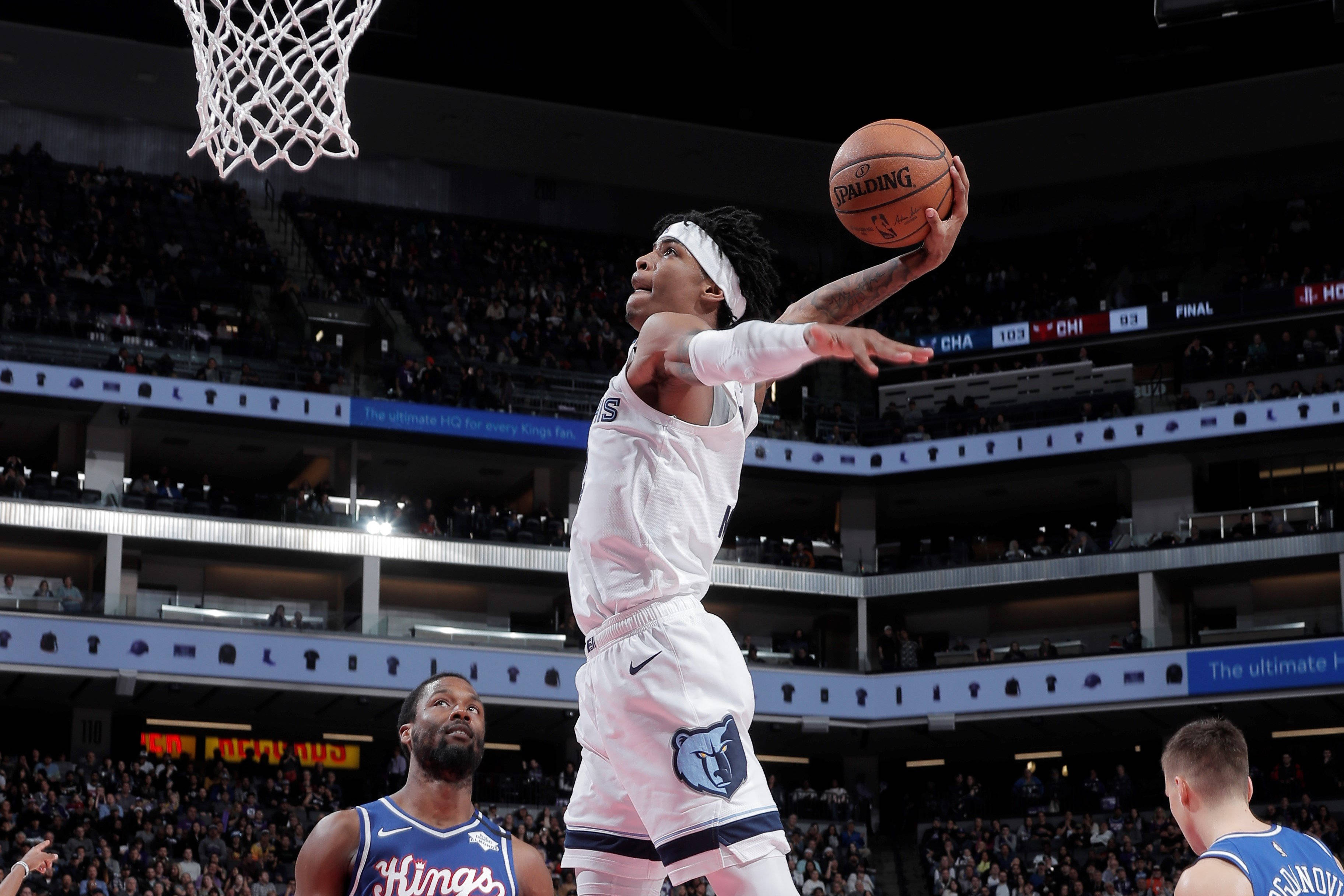Grizzlies 桌布 壁紙 — 一名身穿白色球衣的籃球運動員持球跳向籃框，對手在擠滿觀眾的場館下方觀看。