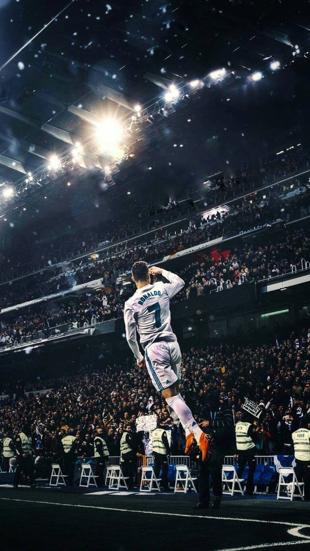 Cristiano Ronaldo 桌布 壁紙 — 一名身穿白色球衣的足球運動員在明亮的泛光燈下，在球場上勝利地跳躍，彩紙飄落。