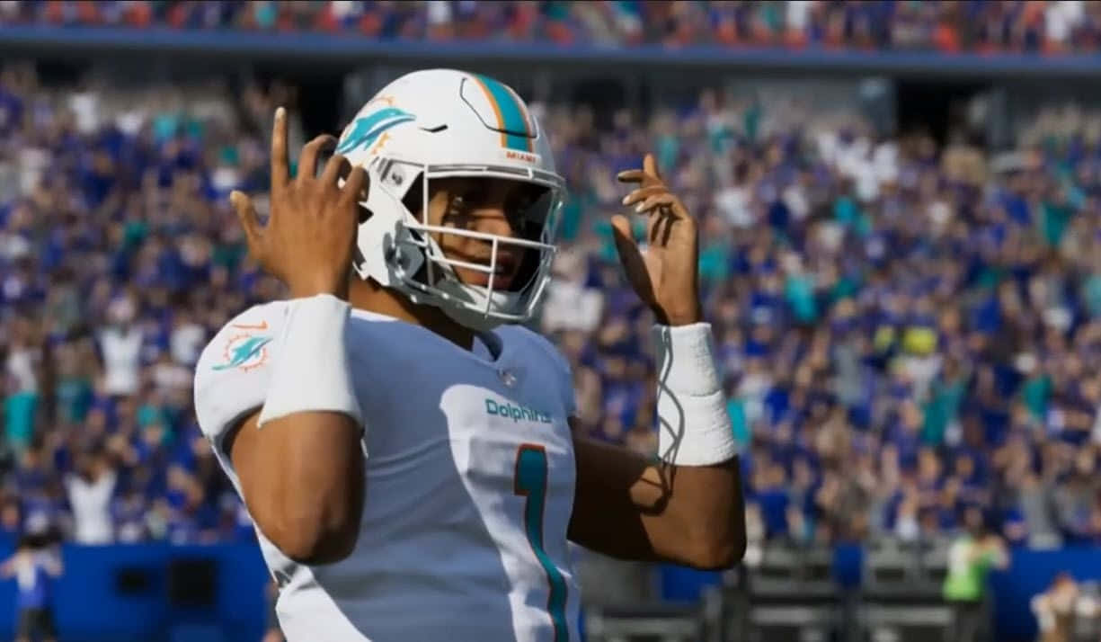 Madden NFL 22 桌布 壁紙 — 一名身穿白色球衣的邁阿密海豚隊四分衛在陽光明媚的足球場上高舉雙手慶祝，背景是模糊的人群。