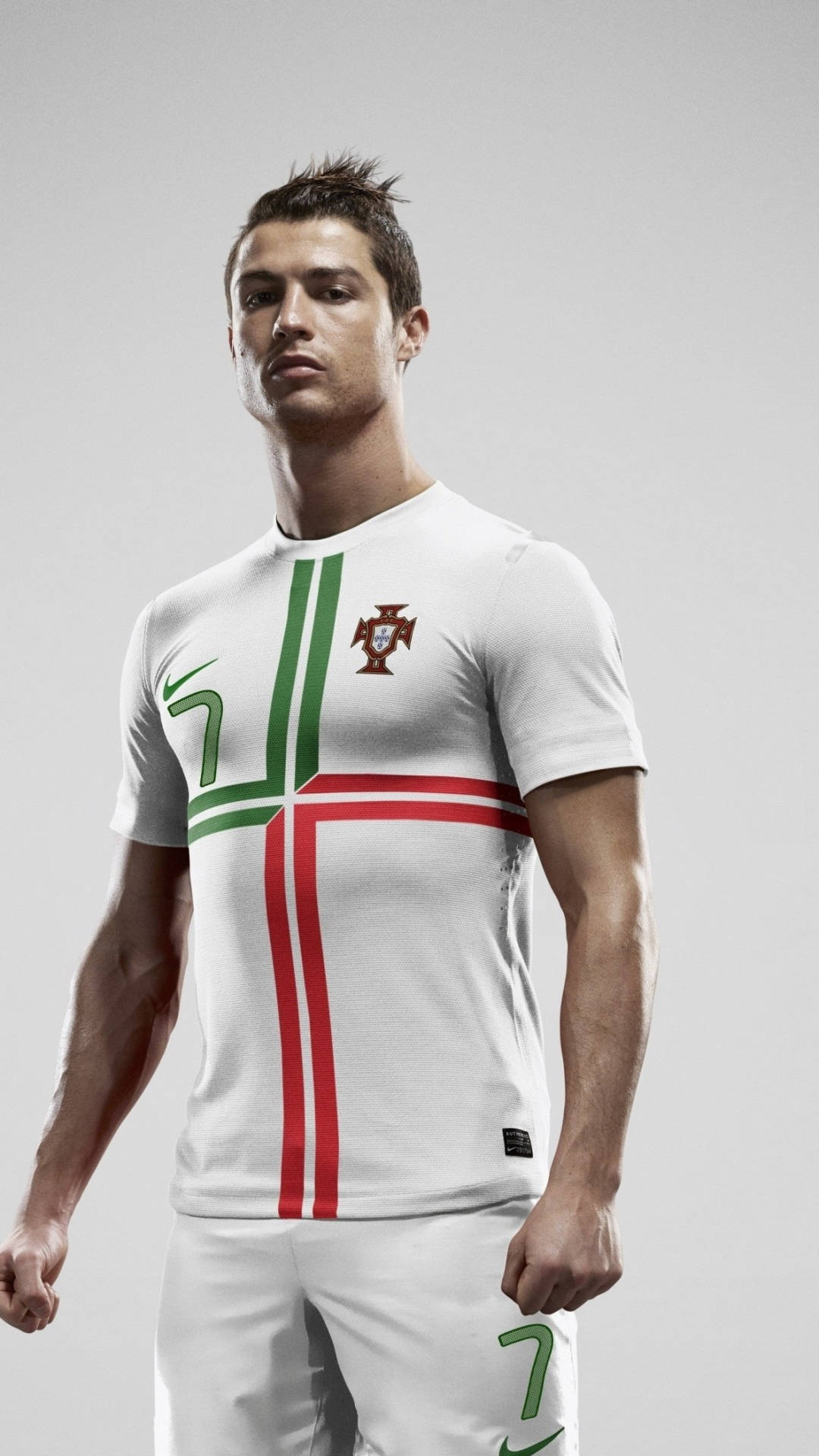 Cristiano Ronaldo 桌布 壁紙 — 一名身穿白色葡萄牙球衣、帶有綠色和紅色條紋的足球員，自信地站在純灰色背景前。