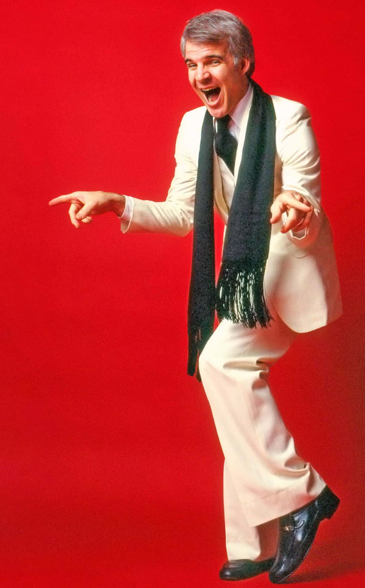 steve martin 桌布 壁紙 — 一名身穿白色西裝和黑色圍巾的男子，在鮮紅色背景前張開嘴巴，帶著喜悅的表情充滿活力地跳舞。