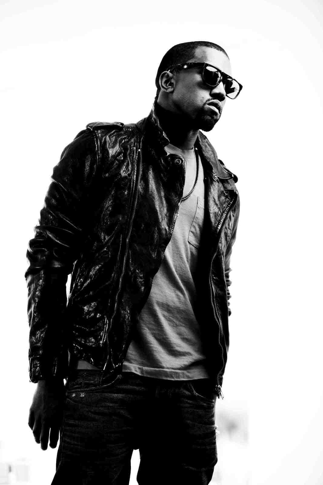 Kanye 桌布 壁紙 — 一名身穿皮褸和太陽眼鏡的男子，在純白背景前以高對比黑白風格自信地站立。