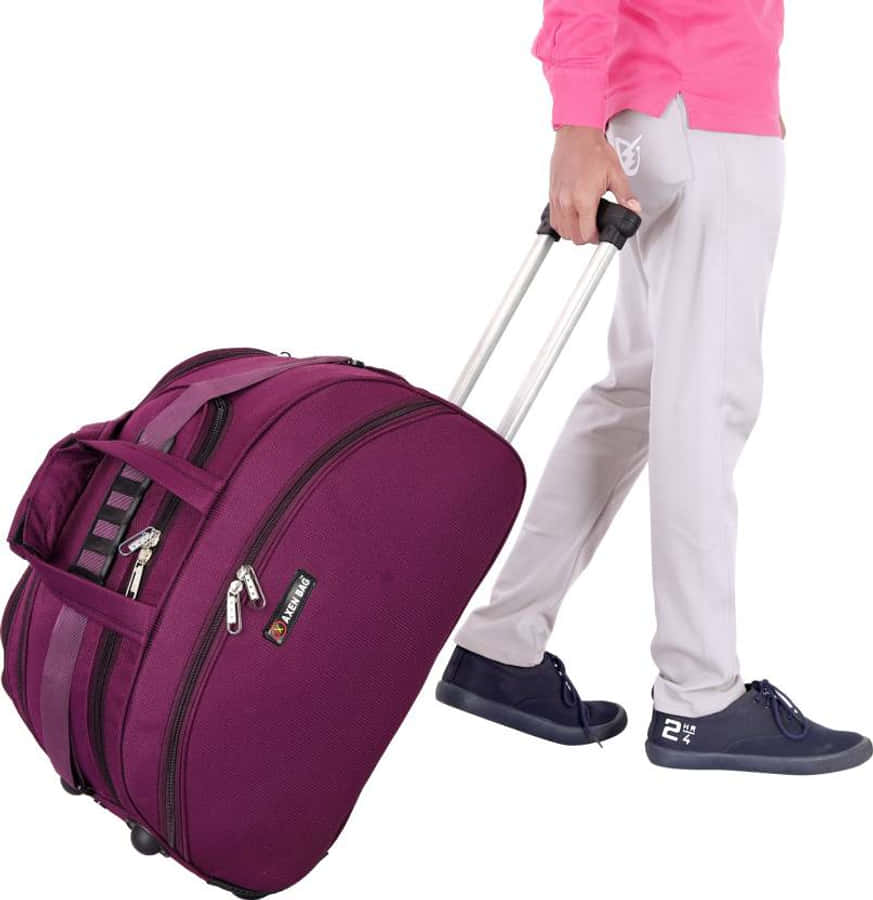 Purple Suitcase 桌布 壁紙 — 一名身穿粉紅色襯衫和灰色褲子的人，拖著一個帶有黑色輪子和拉鏈的紫色滾輪行李袋。