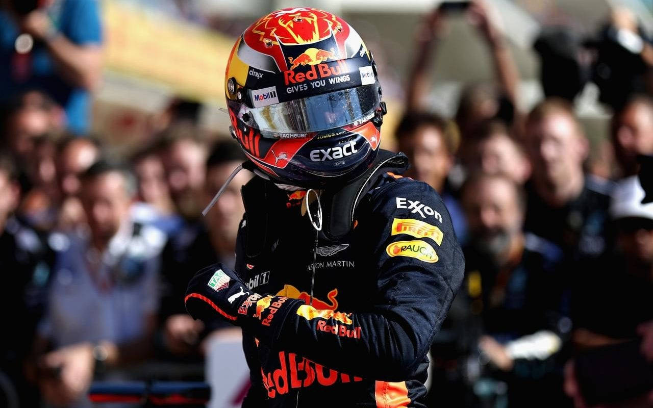 Verstappen 桌布 壁紙 — 一名身穿紅牛賽車服和頭盔的一級方程式車手在歡呼的人群前交叉雙臂慶祝。
