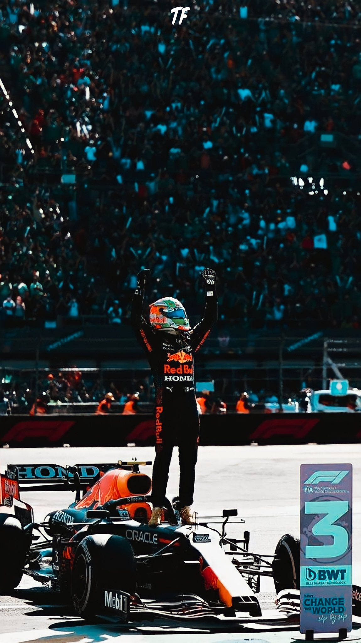 sergio perez 桌布 壁紙 — 一名身穿紅牛賽車服的F1車手站在他的橙色和黑色賽車上，高舉雙臂慶祝勝利，五彩紙屑灑落在擠滿人的體育場上。
