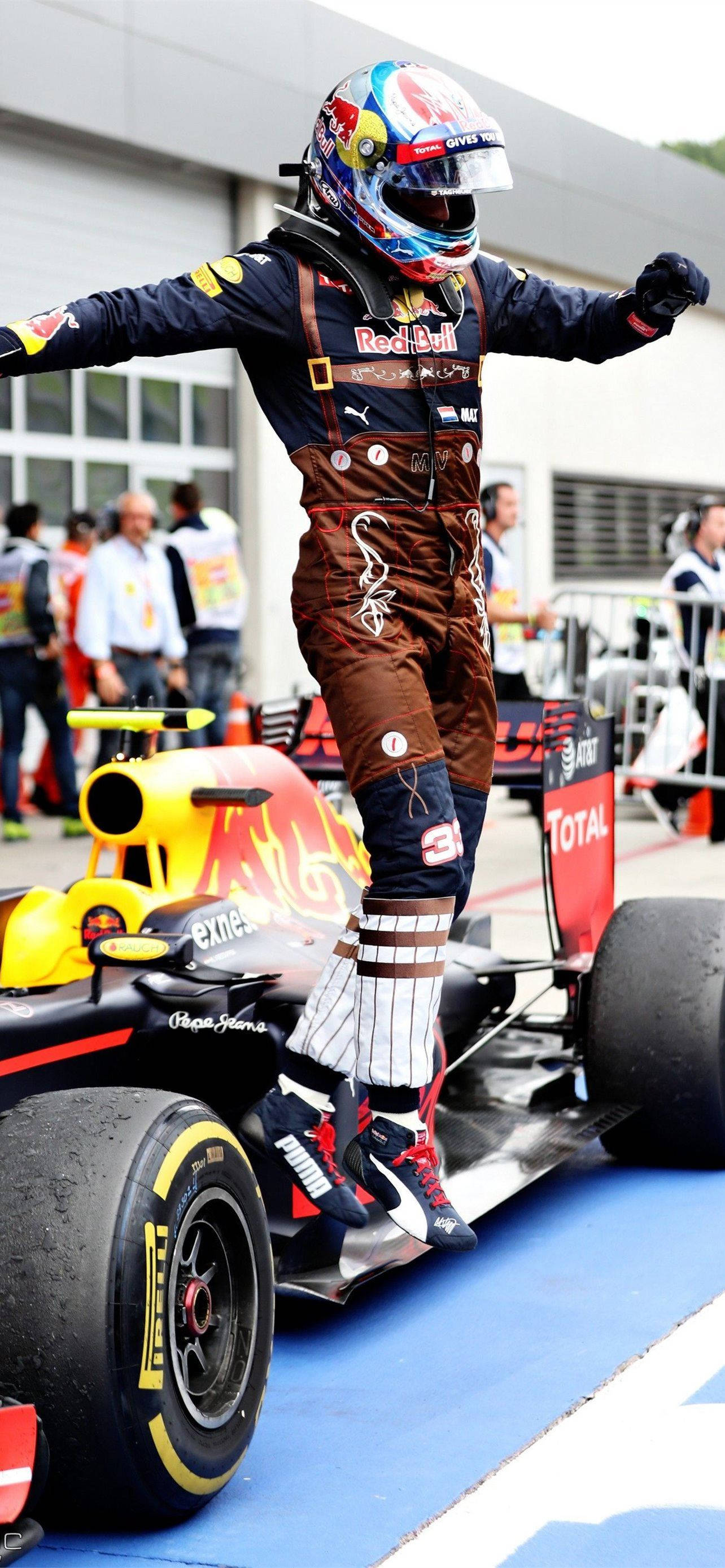 Verstappen 桌布 壁紙 — 一名身穿紅牛賽車裝備的一級方程式車手在藍色維修區通道上，站在他的黃黑賽車頂上慶祝勝利。