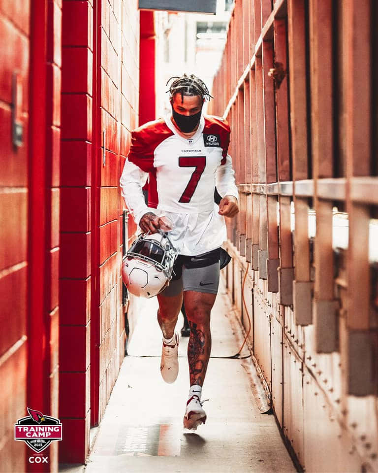 Byron Murphy 桌布 壁紙 — 一名身穿紅白 Cardinals 球衣的足球員，手持頭盔，沿著狹窄的紅磚走廊奔跑。