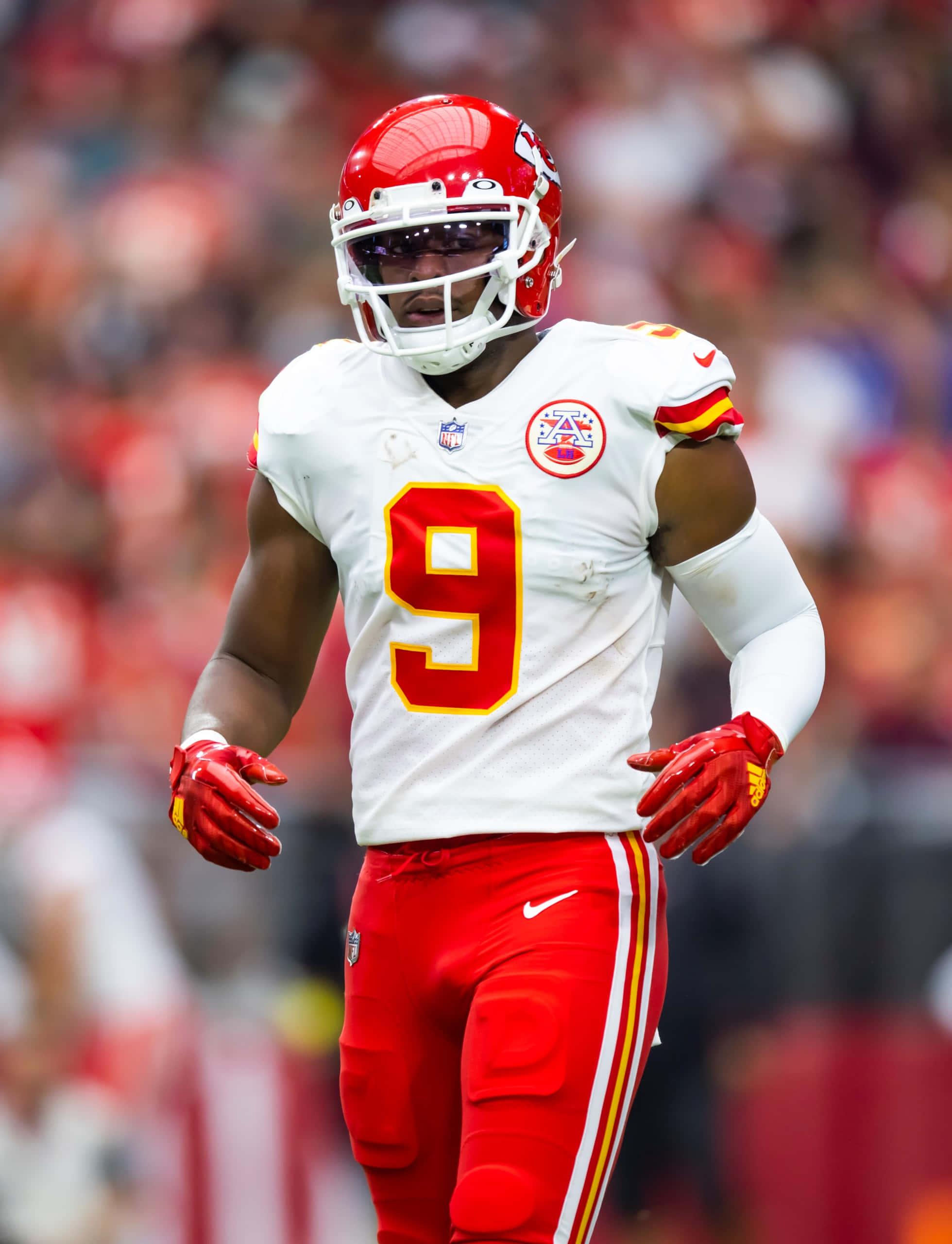 Juju Smith Schuster 桌布 壁紙 — 一名身穿紅白球衣、背號9號的足球員在比賽中走過球場，背景是模糊的體育場人群。