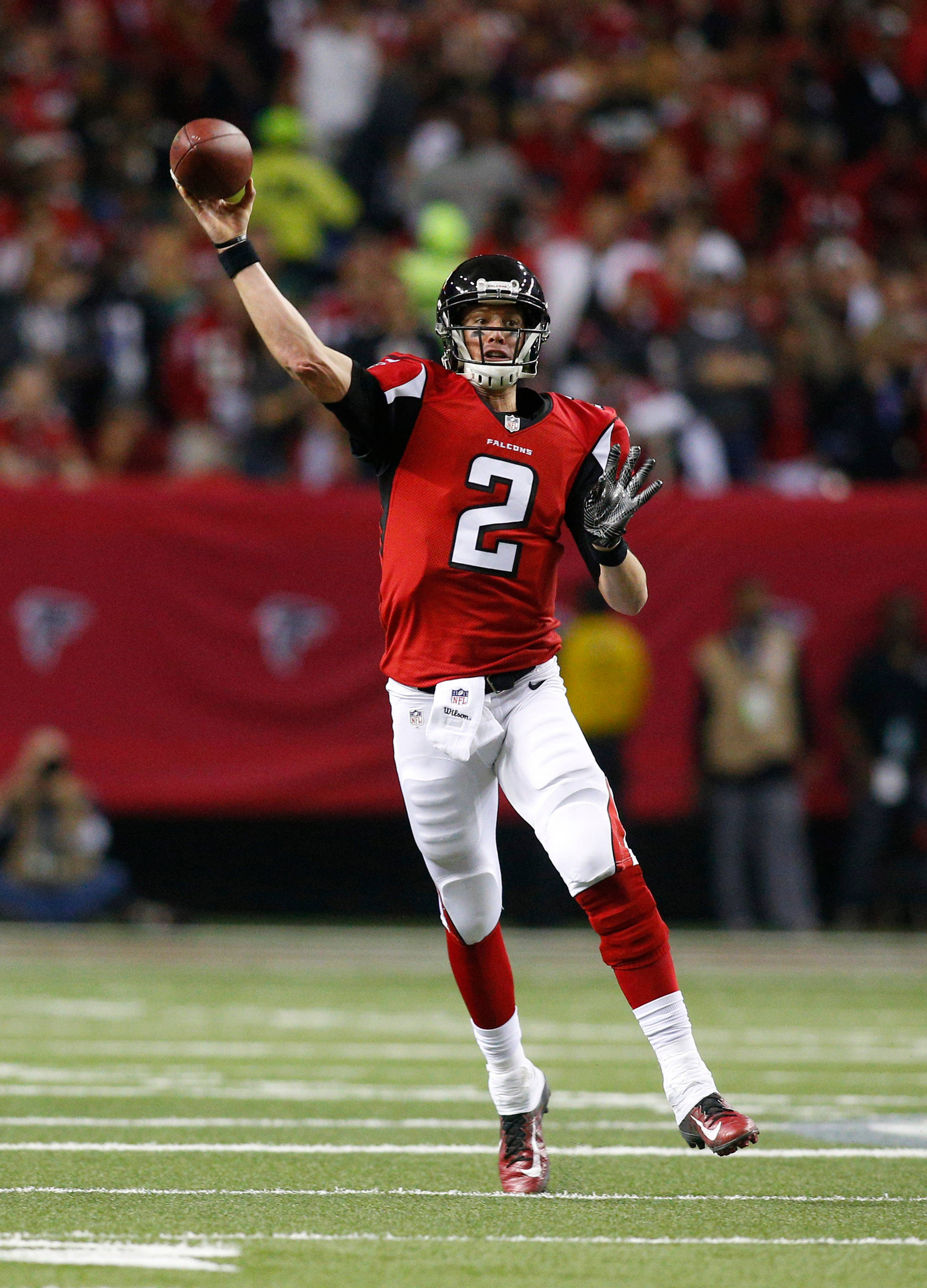 Matt Ryan 桌布 壁紙 — 一名身穿紅白球衣的美式足球四分衛在比賽中擲球，背景是模糊的人群。