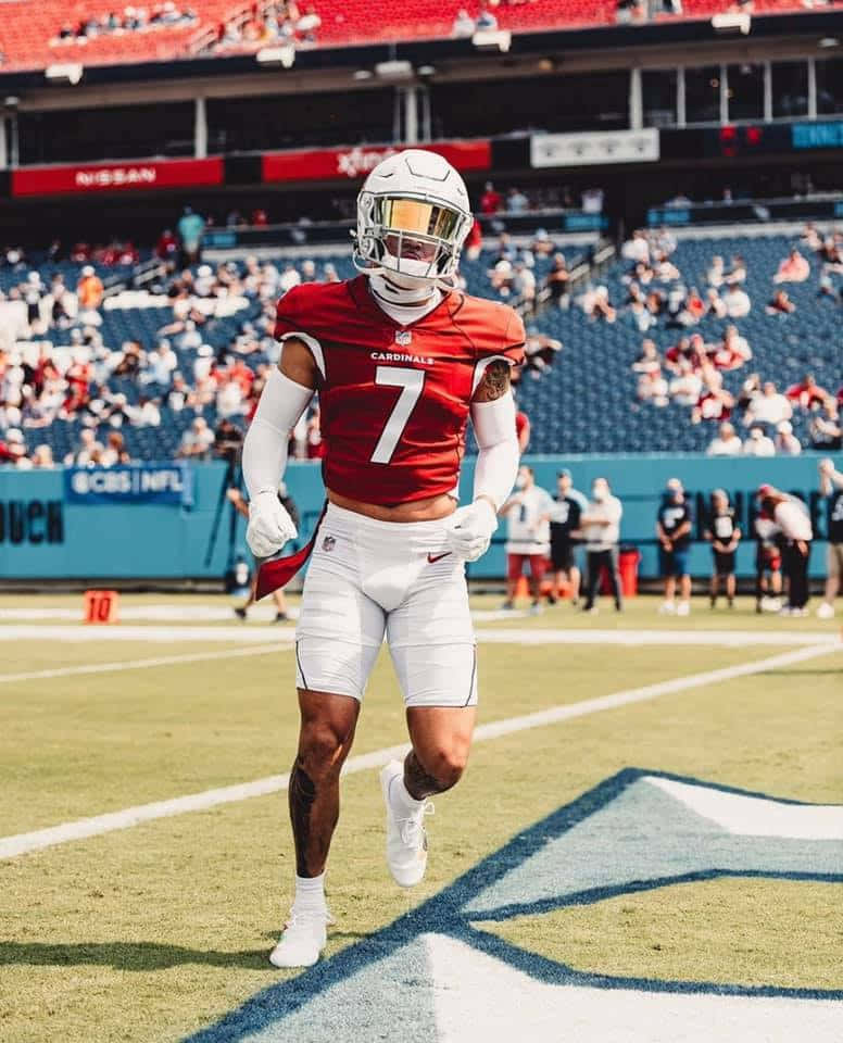 Byron Murphy 桌布 壁紙 — 一名身穿紅色 Cardinals 7 號球衣的美式足球員在陽光明媚的球場上衝刺，看台上坐滿了球迷。