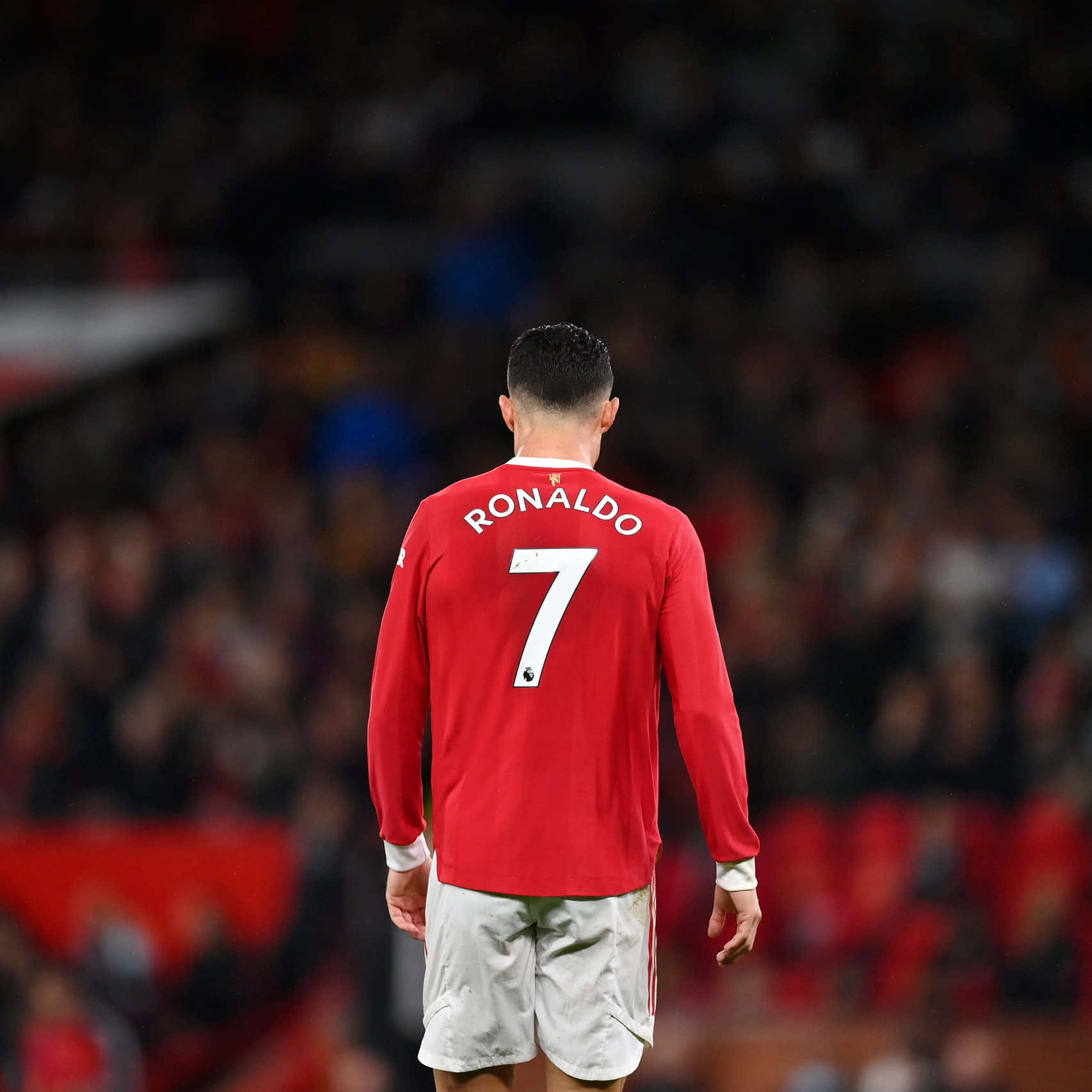 Cristiano Ronaldo 桌布 壁紙 — 一名身穿紅色7號球衣的足球員在球場上背對鏡頭走開，背景是模糊的觀眾。
