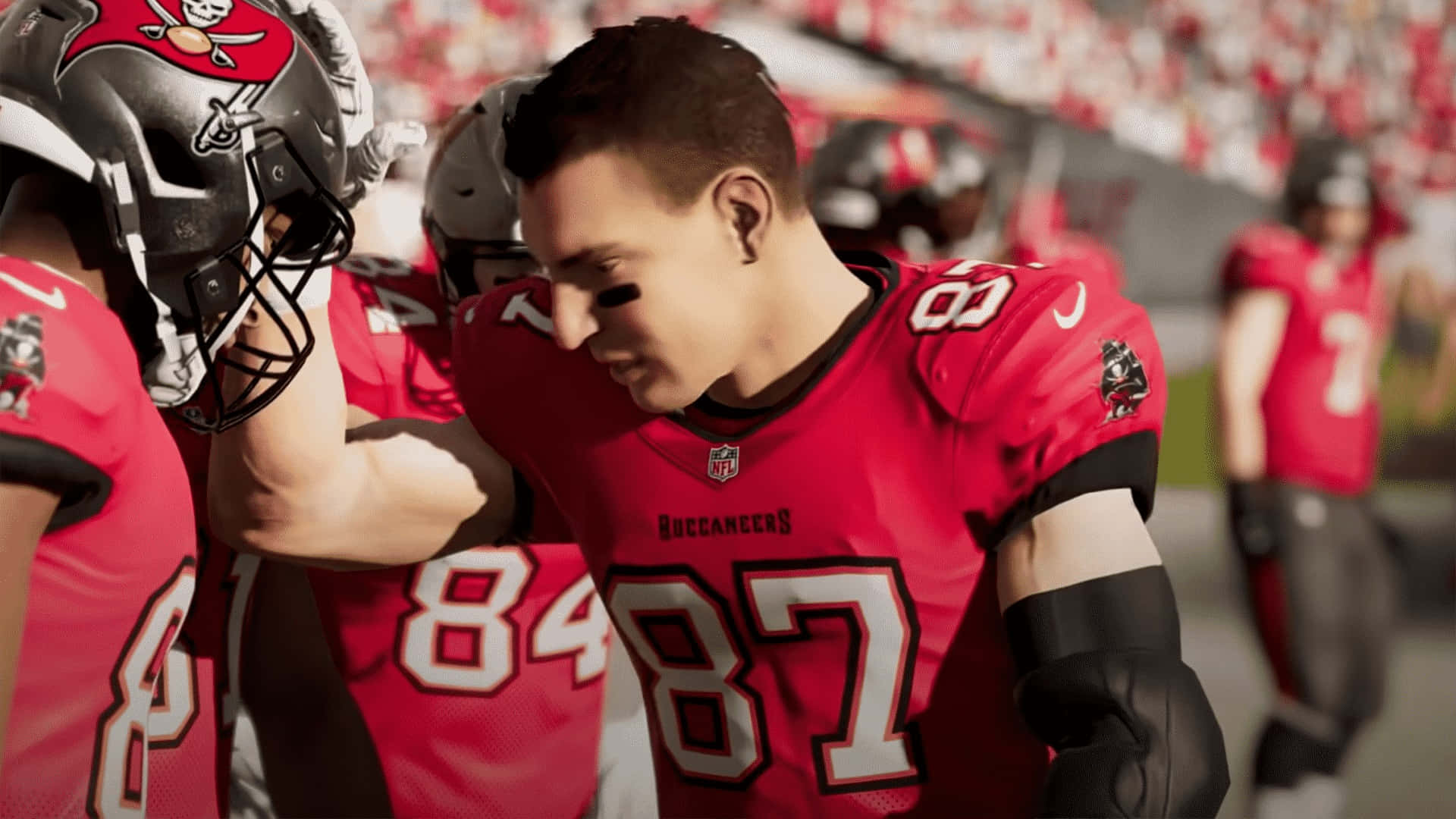 Madden NFL 22 桌布 壁紙 — 一名身穿紅色87號球衣的坦帕灣海盜隊美式足球員在比賽中於球場上擁抱隊友。