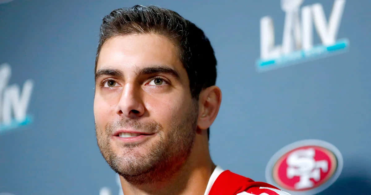 Jimmy Garoppolo 桌布 壁紙 — 一名身穿紅色三藩市49人隊球衣的男子，在藍色背景前帶有LAIV標誌的特寫肖像。
