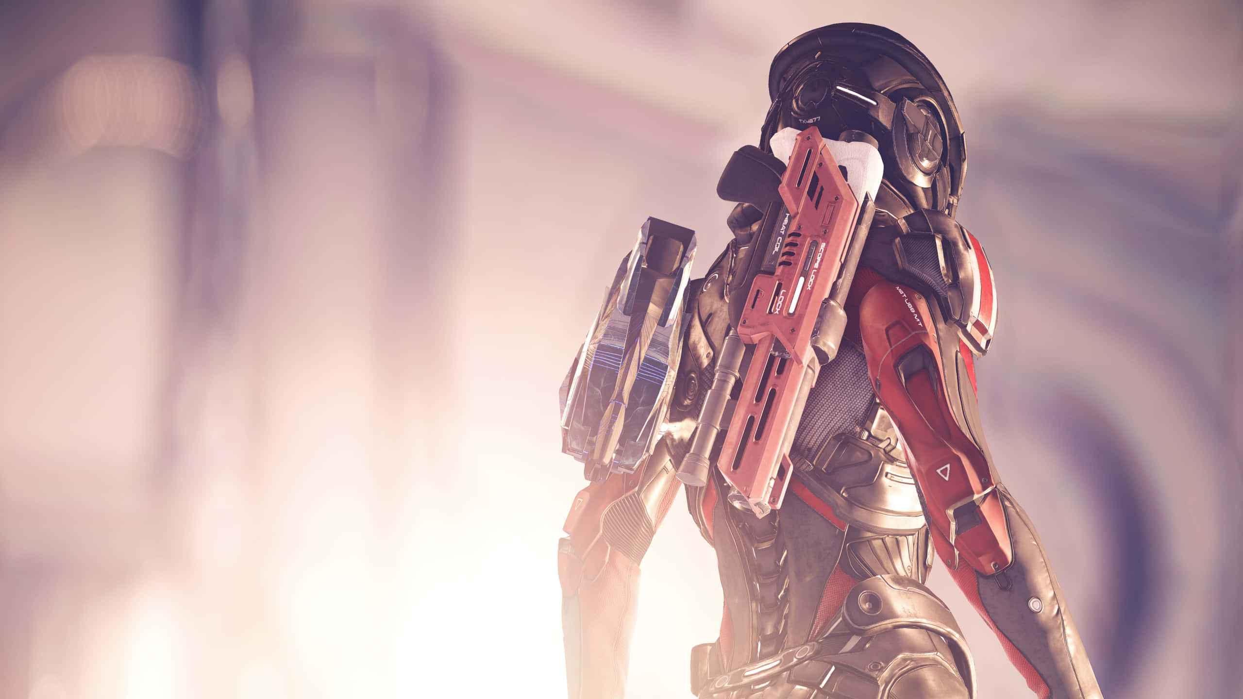 Mass Effect Andromeda 桌布 壁紙 — 一名身穿紅色和黑色盔甲的未来士兵站在朦朧發光的環境中手持武器。