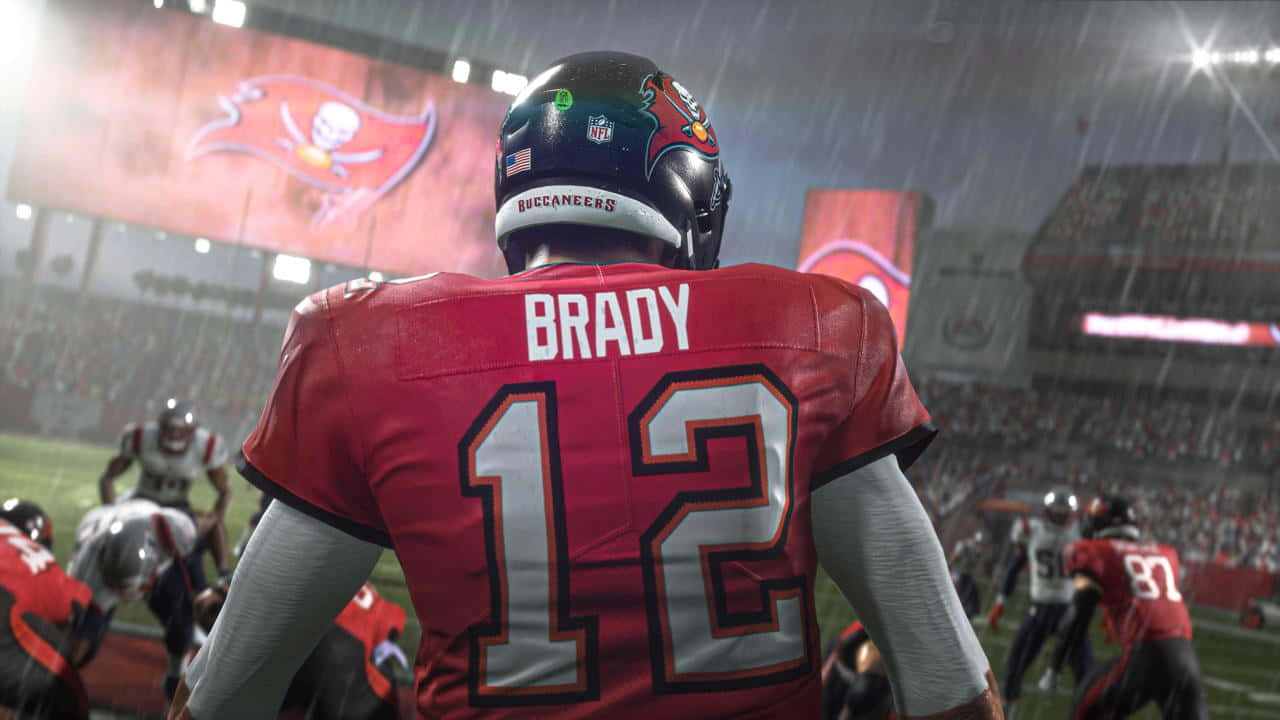 Madden NFL 22 桌布 壁紙 — 一名身穿紅色坦帕灣海盜隊12號球衣的美式足球員站在球場燈光下、被雨水浸濕的場地上。