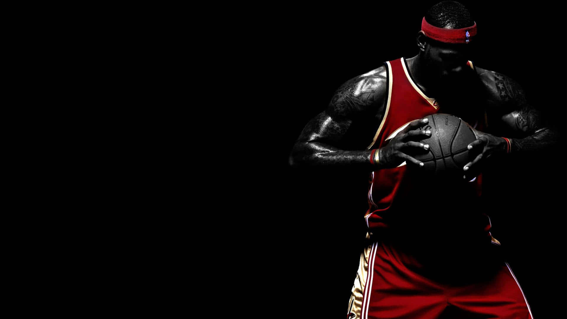 Minimalist Sports 桌布 壁紙 — 一名身穿紅色球衣的籃球運動員在強烈黑色背景下，以戲劇性燈光手持籃球。