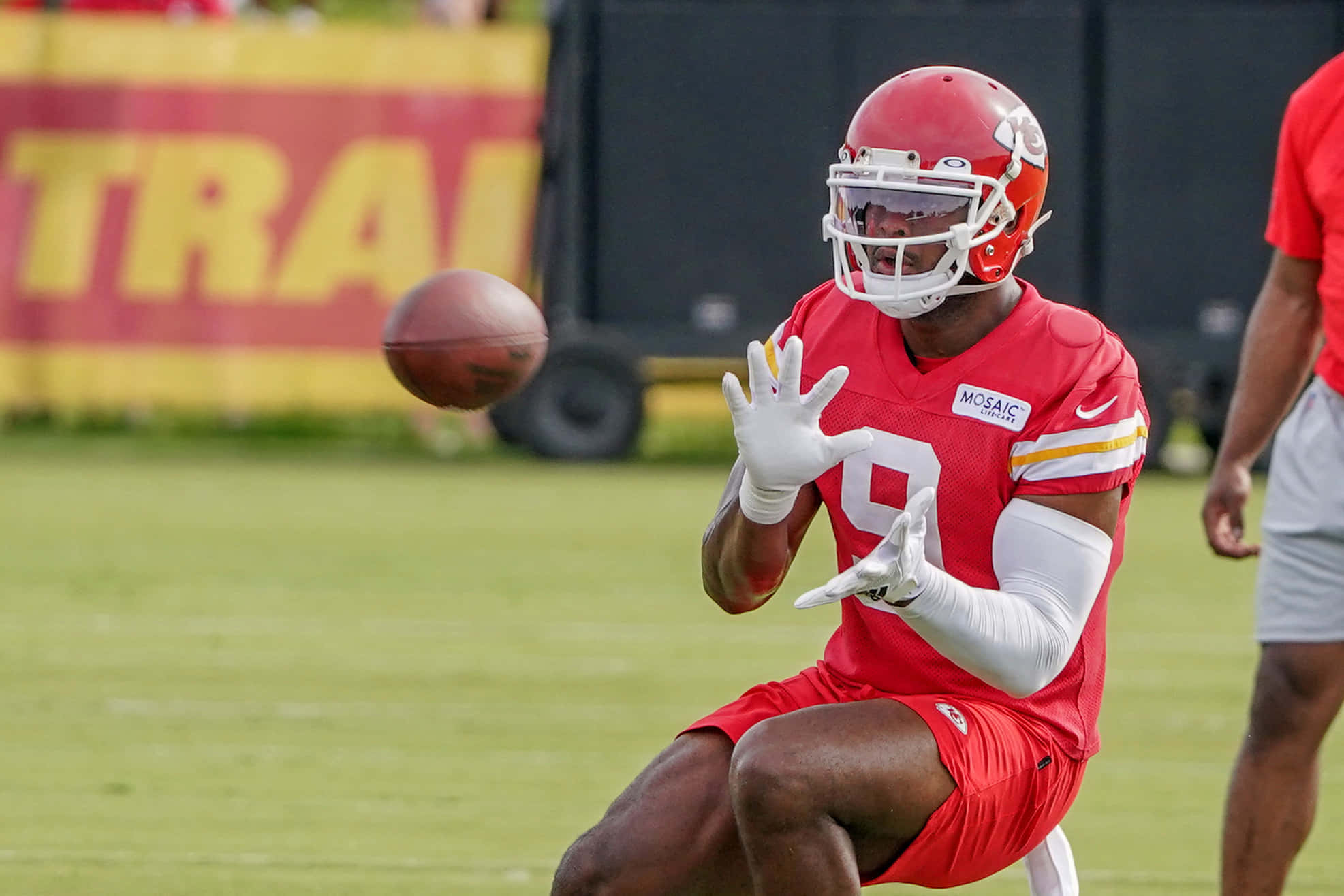 Juju Smith Schuster 桌布 壁紙 — 一名身穿紅色球衣的足球運動員在綠色場地上訓練時，在空中接住了一個球。