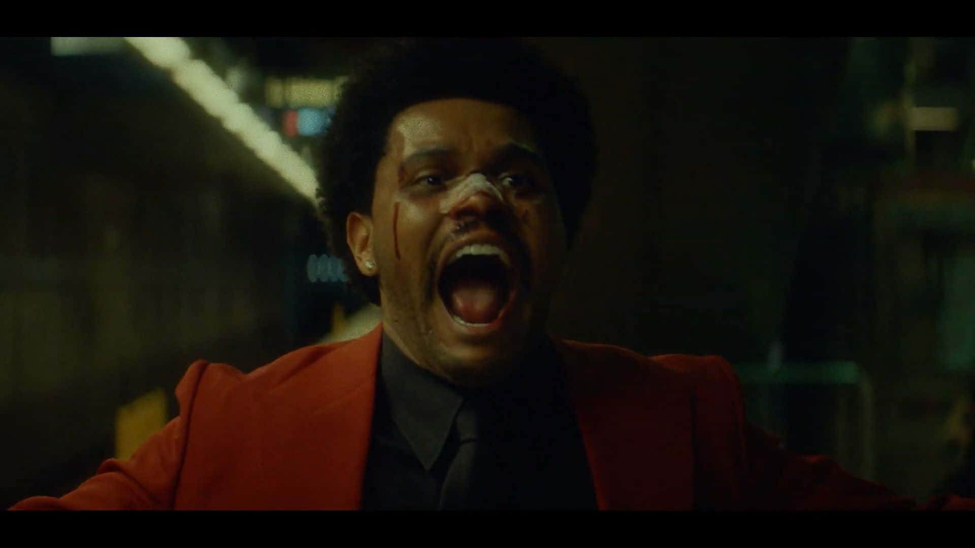 The Weeknd After Hours 桌布 壁紙 — 一名身穿紅色西裝的男子在昏暗的霓虹燈下，於骯髒的城市小巷中滿臉鮮血地尖叫。